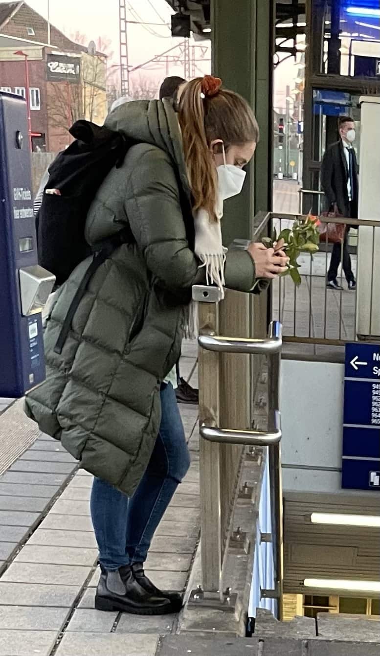 junge Frau wartet auf Bahnsteig mit Rose