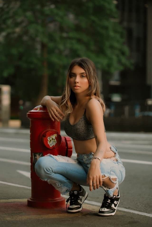 junge Frau kniend vor Hydranten