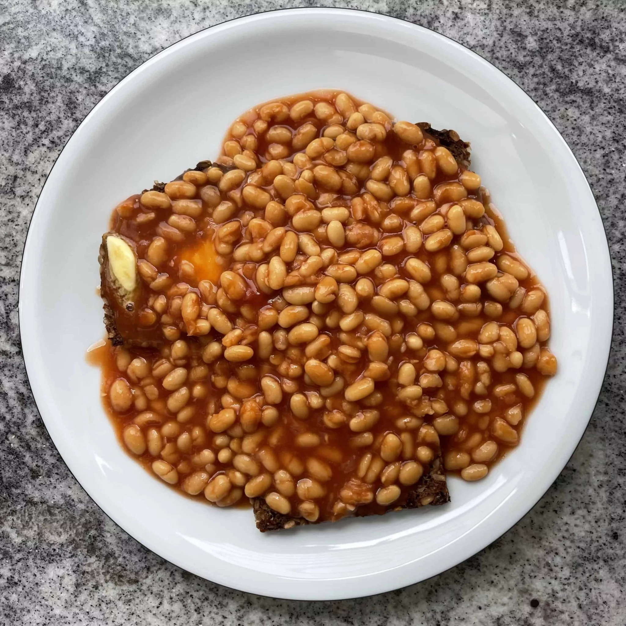 Teller weiße Bohnen in roter Soße auf gebuttertem Brot