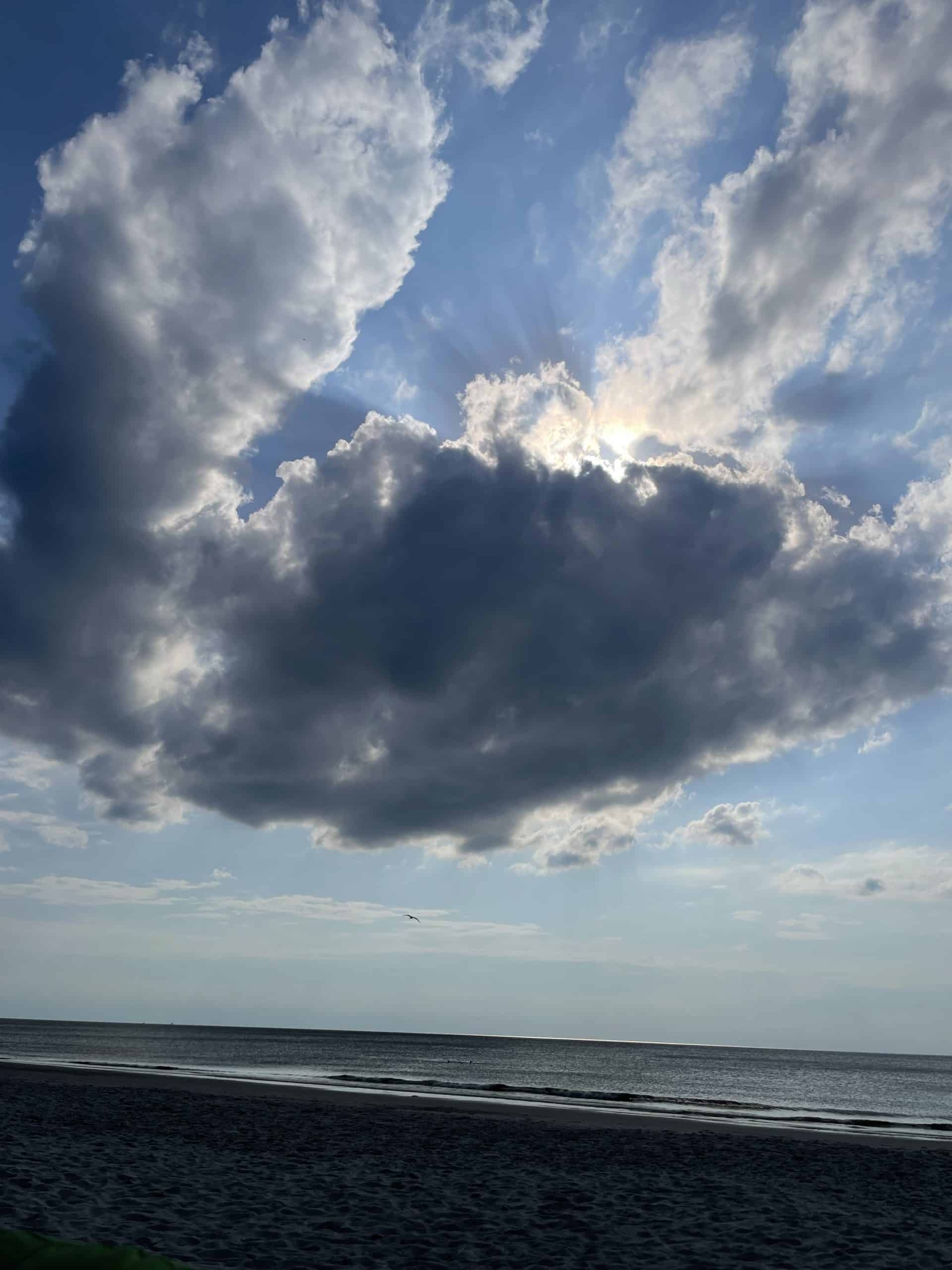 wolkiger Himmel vor Strand und Meer