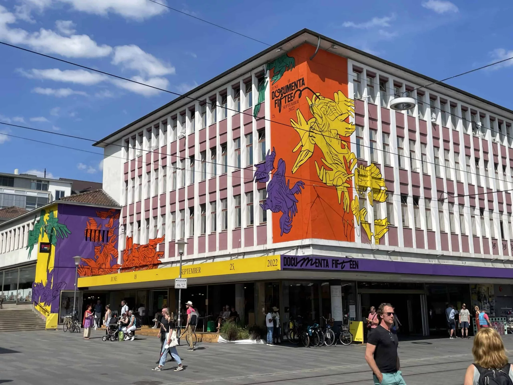 Weißes Documenta-Hausmit gelb, orangen und lila Drachen im Comic-Stil geschmückt.