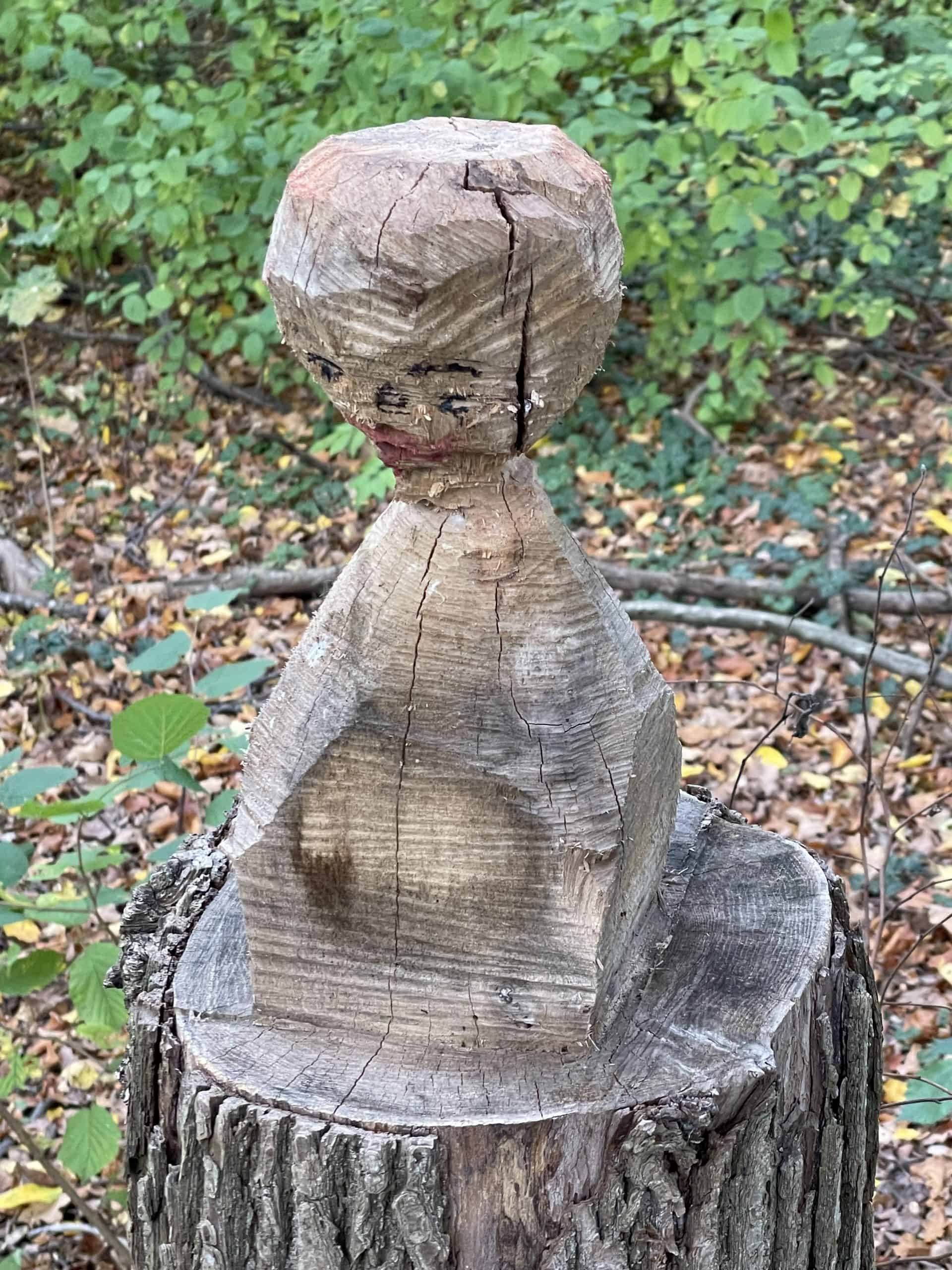 Holzfigur auf Baumstamm im Wald
