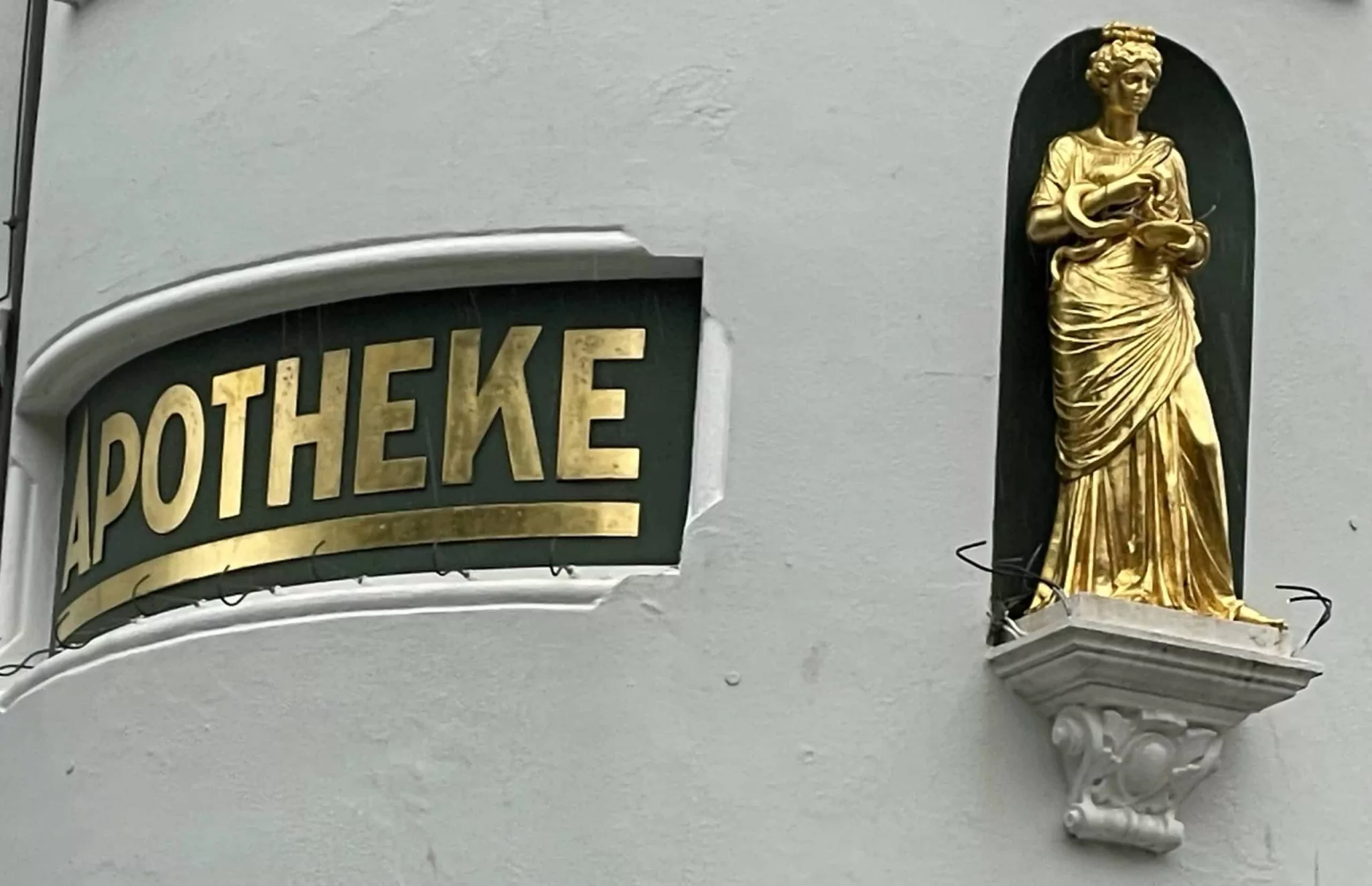 goldener Apothekenschriftzug mit goldener weiblicher Figur