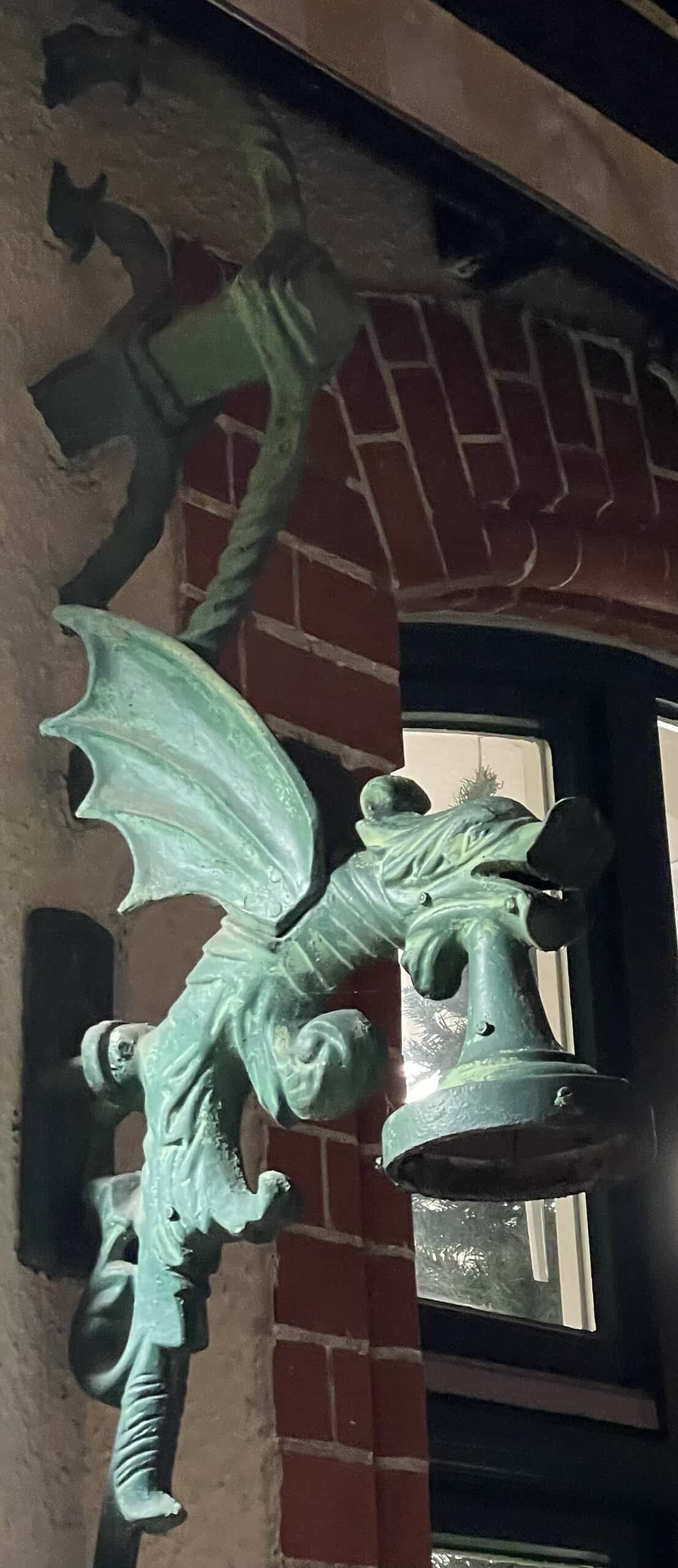 Grüner Metaldrache als Keuchtenhakter an der Fassade des Kurhausea Friedenstal.