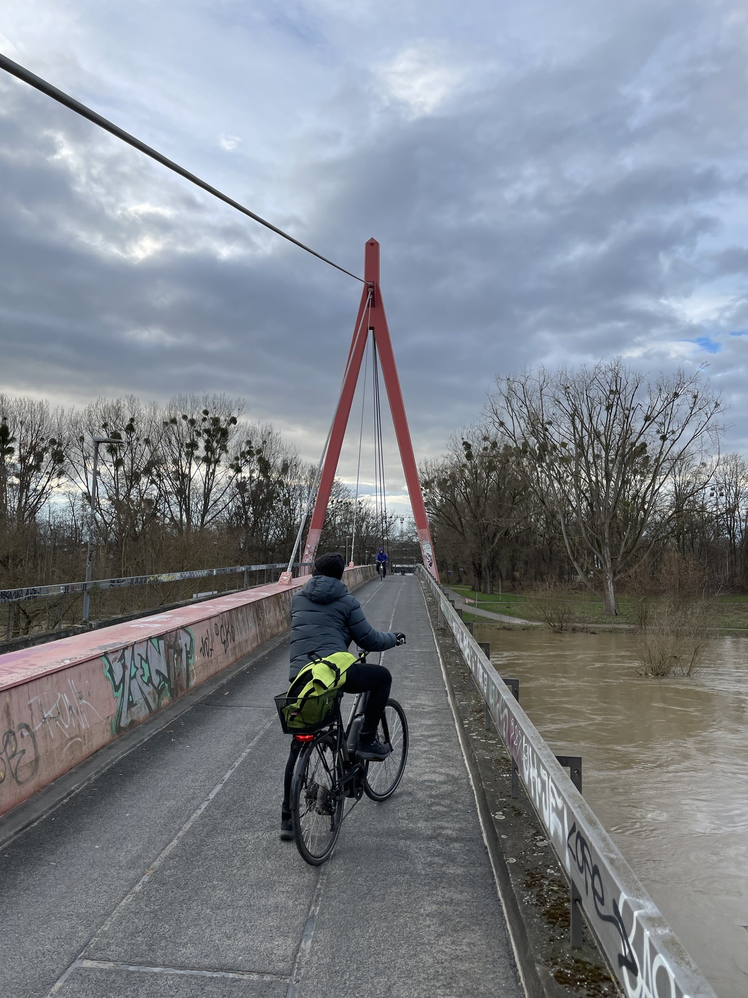 Brücke über die Ihme mit Spannvorrichtung und haltender Radfahrerin im Vordergrund.
