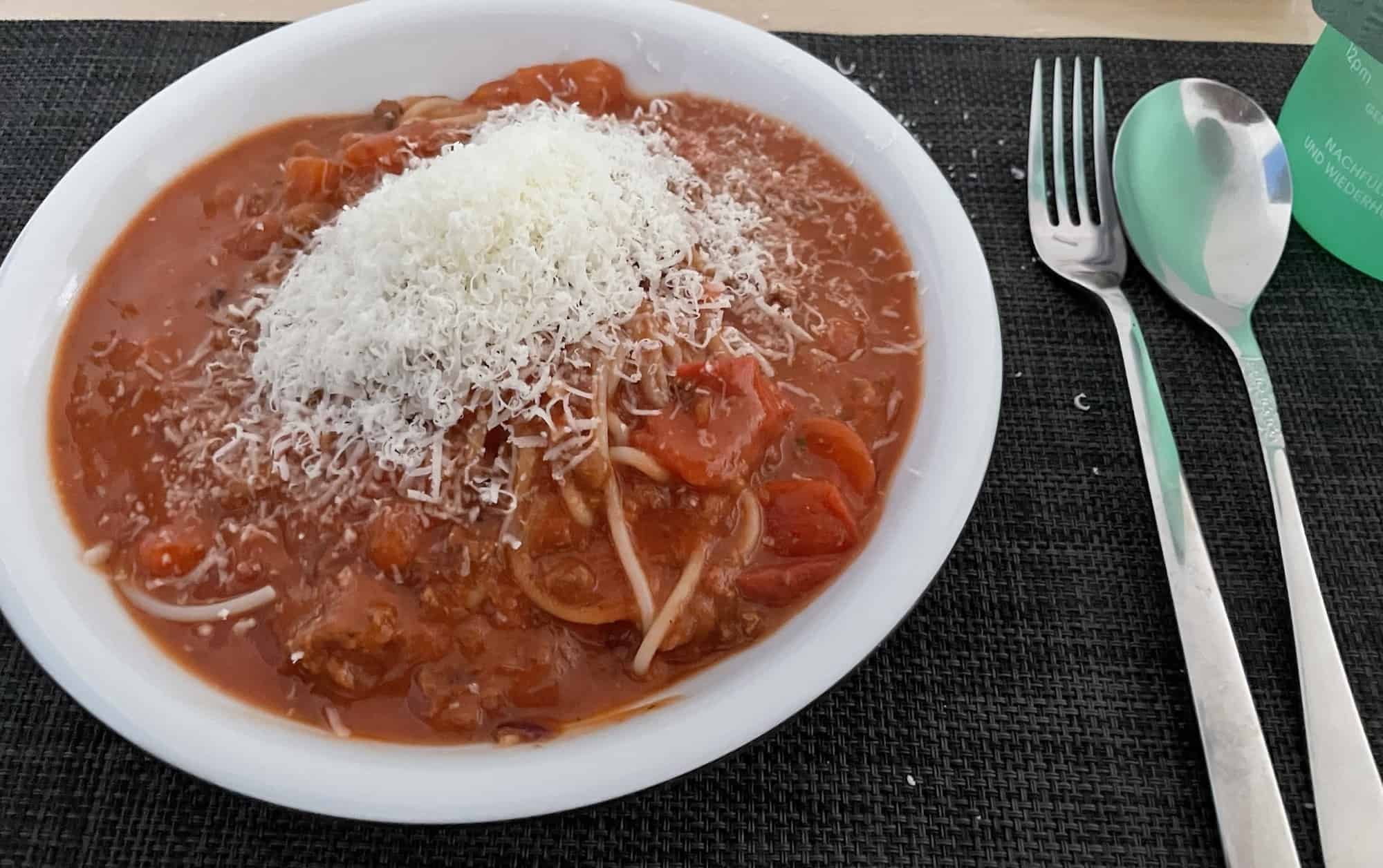 In Bolognesesoße ersoffene Spaghetti mit geriebenem Parmesan 