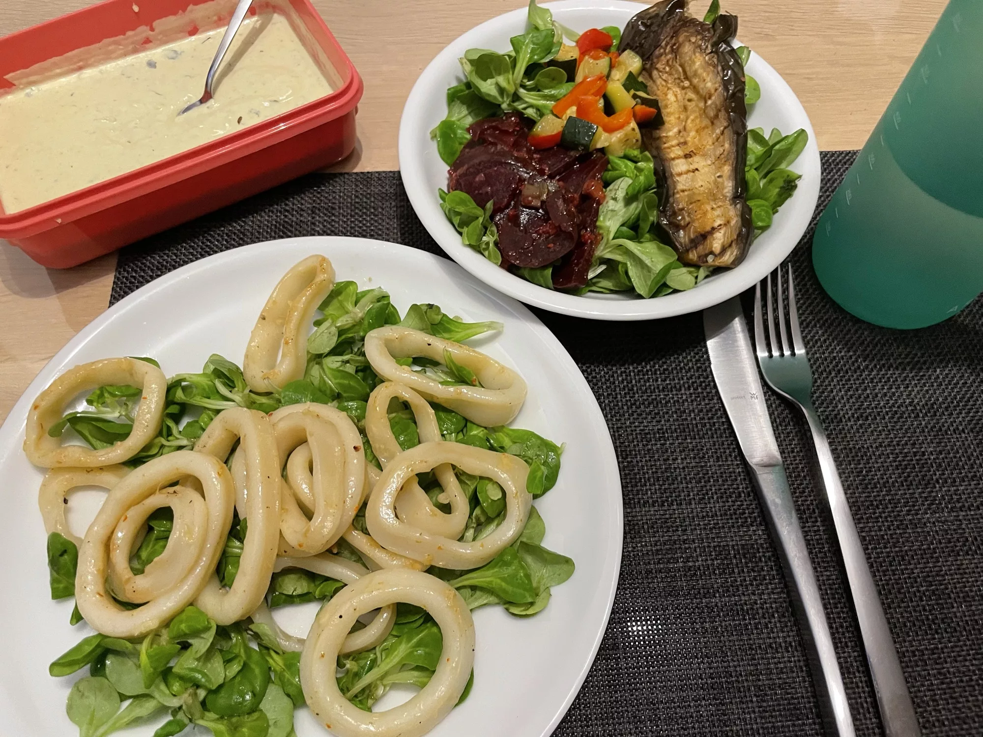 Tintenfischringe auf grünem Salat mit Aioli und einem kleinen gemischten Salat.