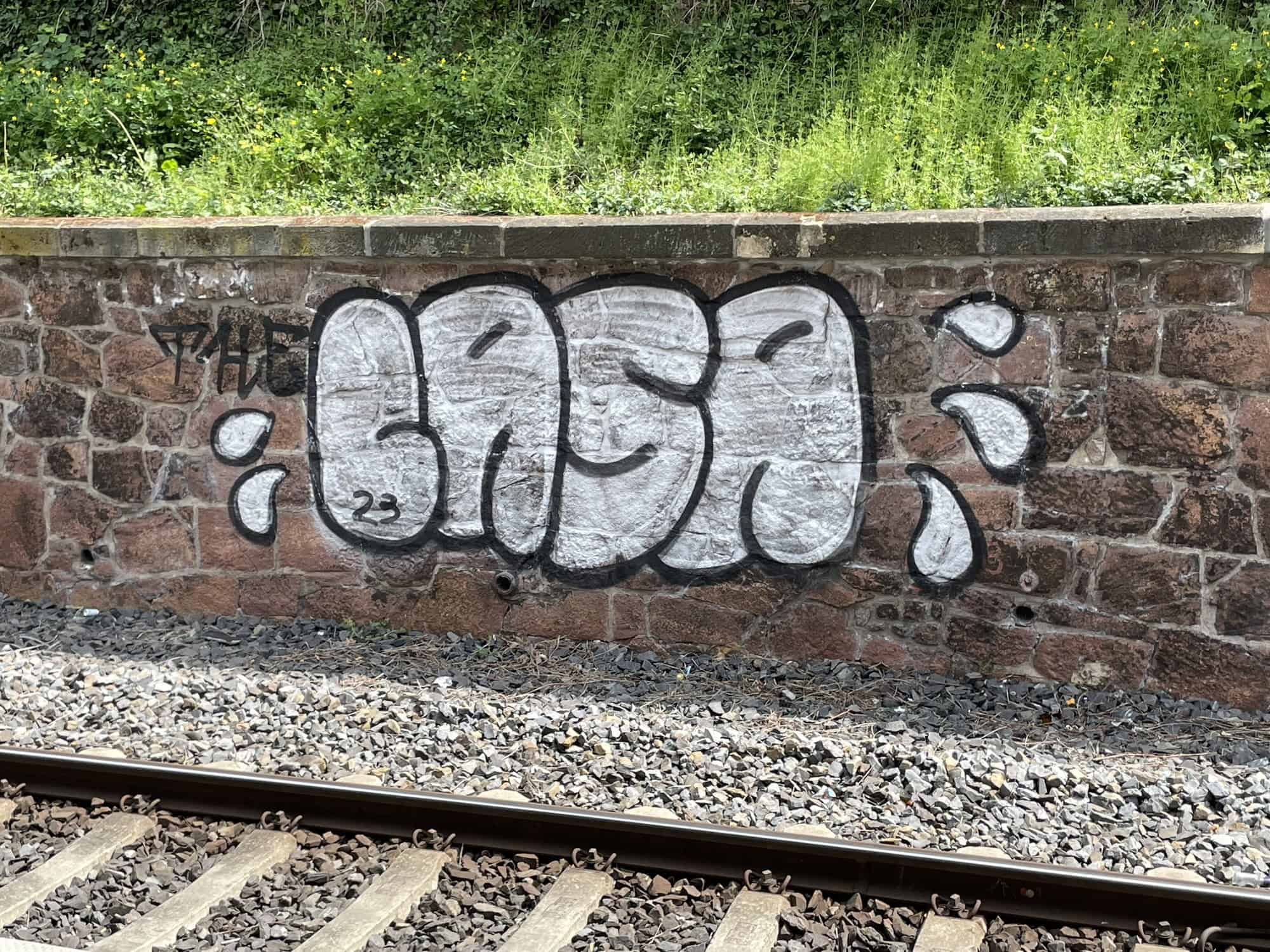 Mauer an der Bahn beim Meißener Bahnhof mit weißem Graffiti-Schriftzug.