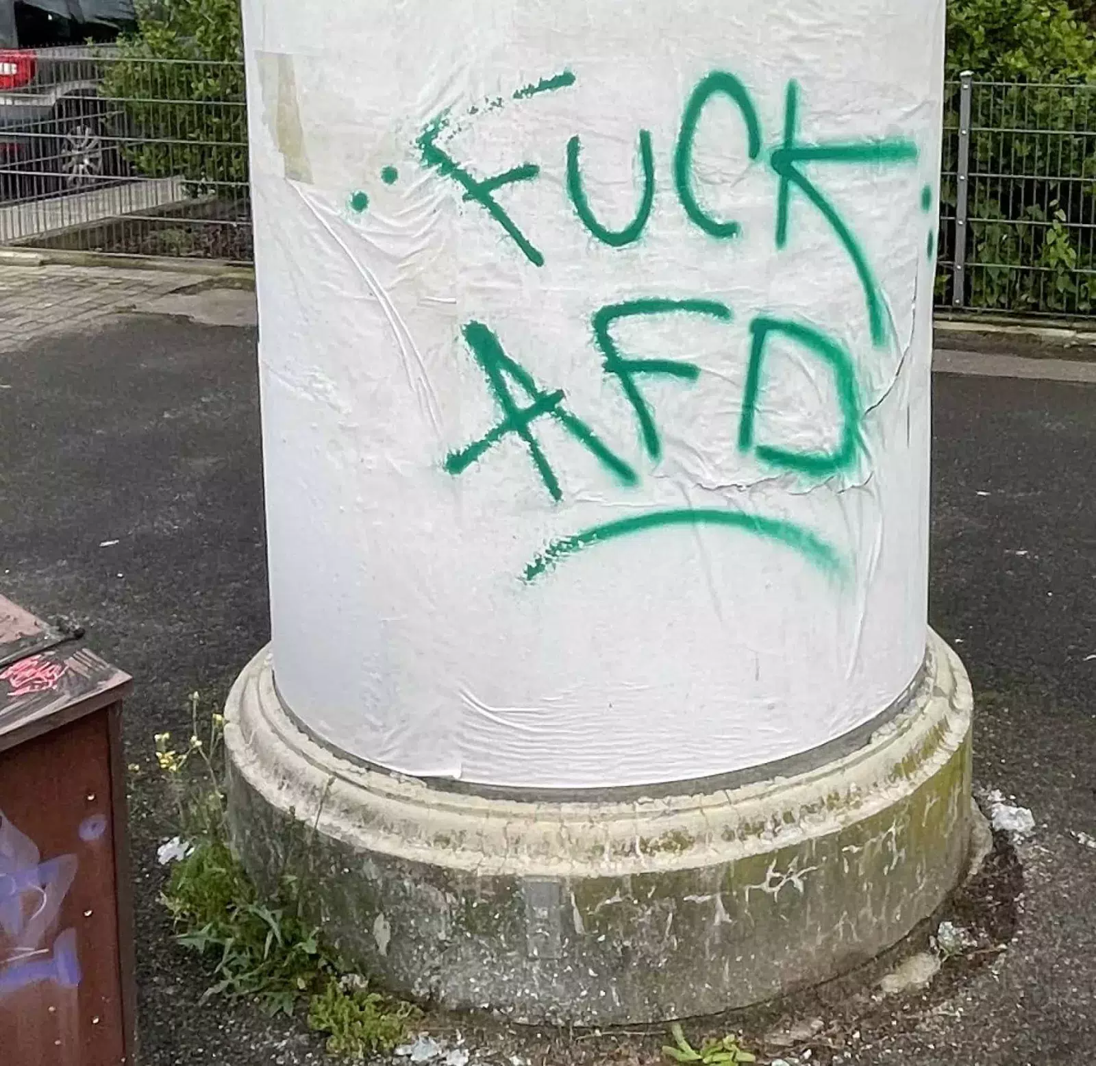 Litfaßsäule unten, weiß ohne Reklame mit grünem ‚Fuck AfD‘ Spraying.