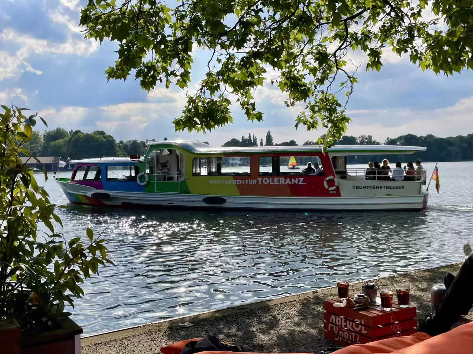 Ein regenbogenfarbenes Maschseebotauf eben diesem fahrend mit der Aufschrift: WIR FAHREN FÜR TOLERANZ. <img decoding=