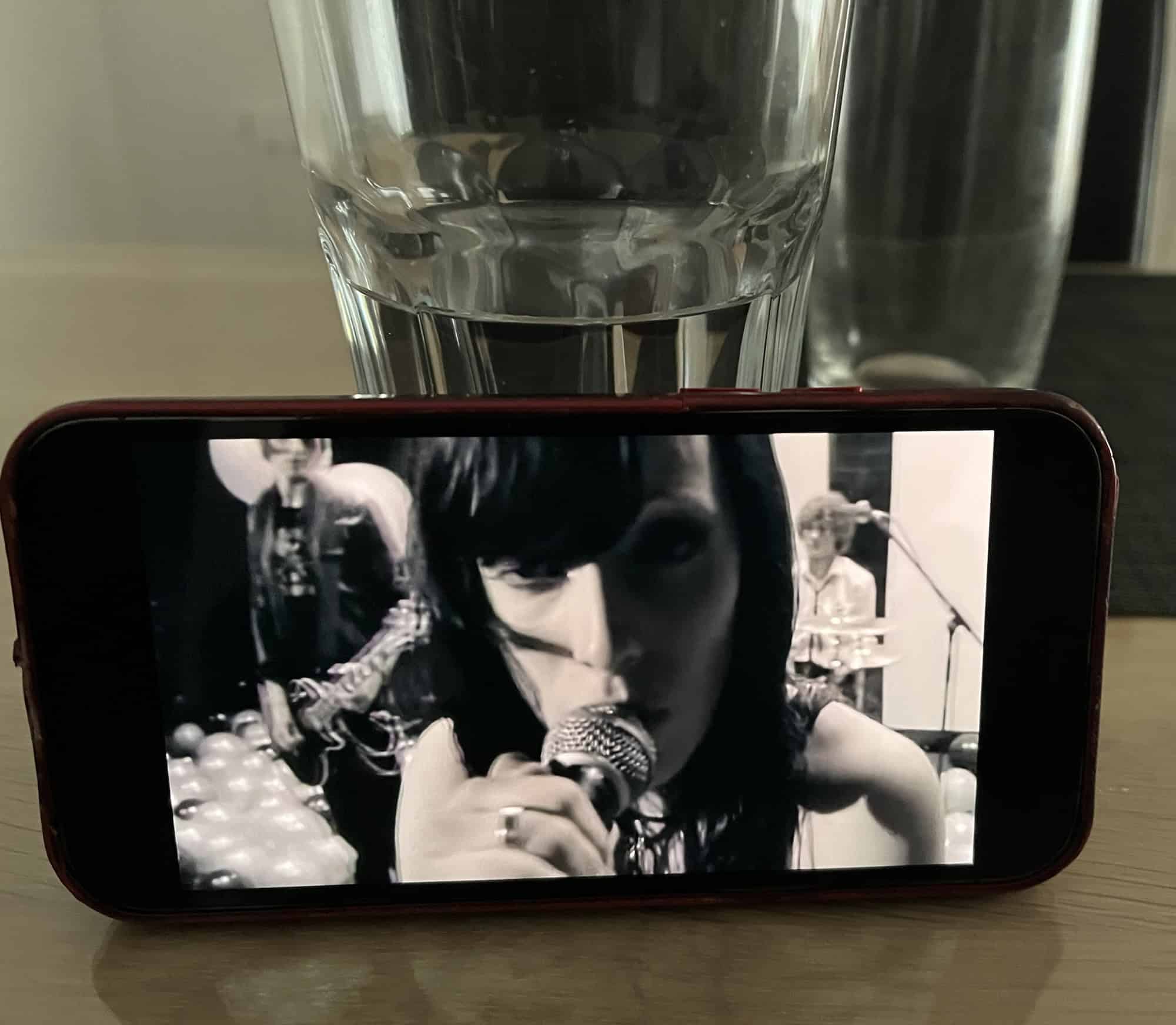 iPhone auf Tisch an Wasserglaslehnend und Silbermind-Musikvideo Symphonie mit singender Stefanie Kloß.