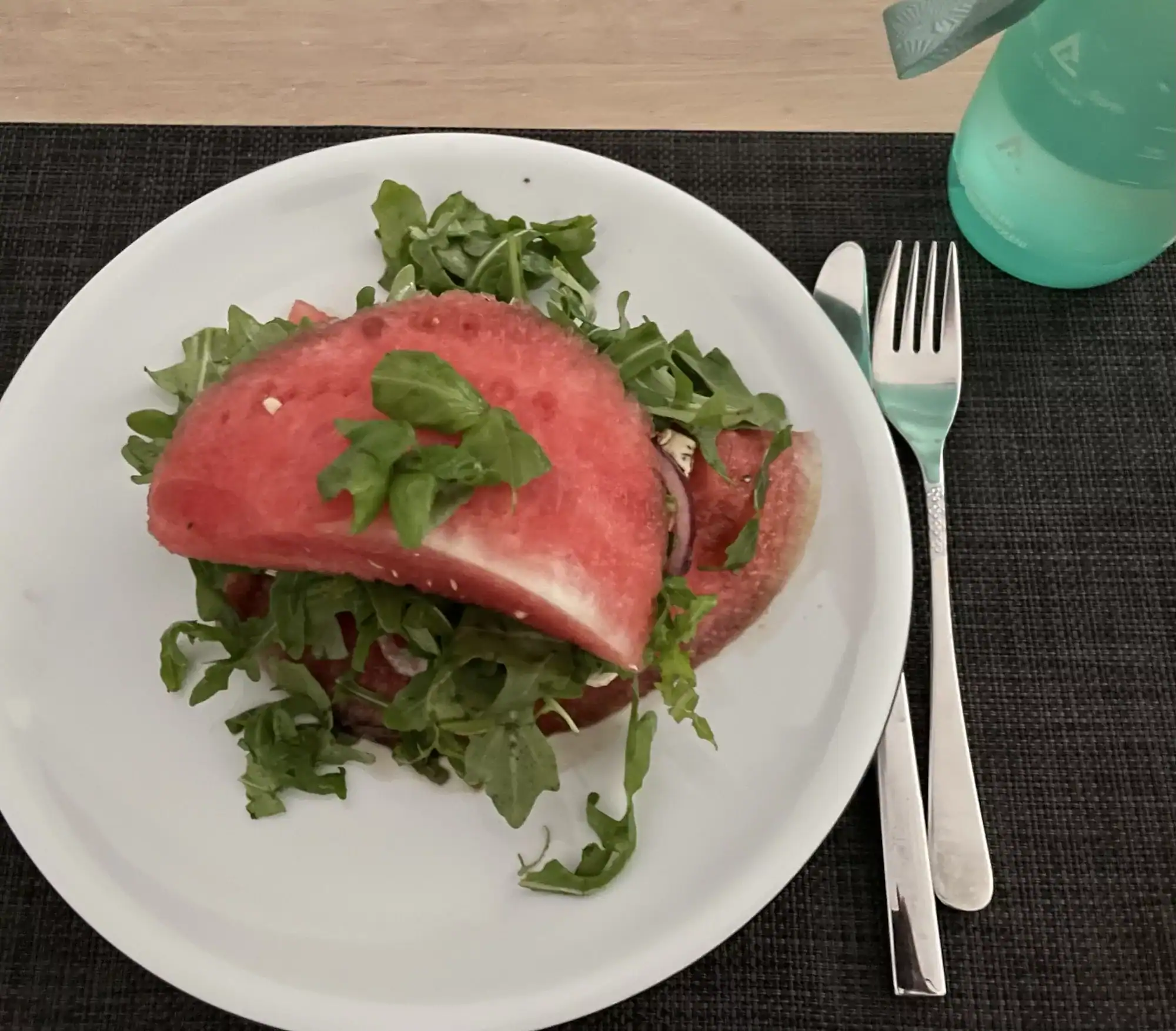 Stück Wassermelone mit Fetafüllung, Balsamicoessig und Rucolasalat