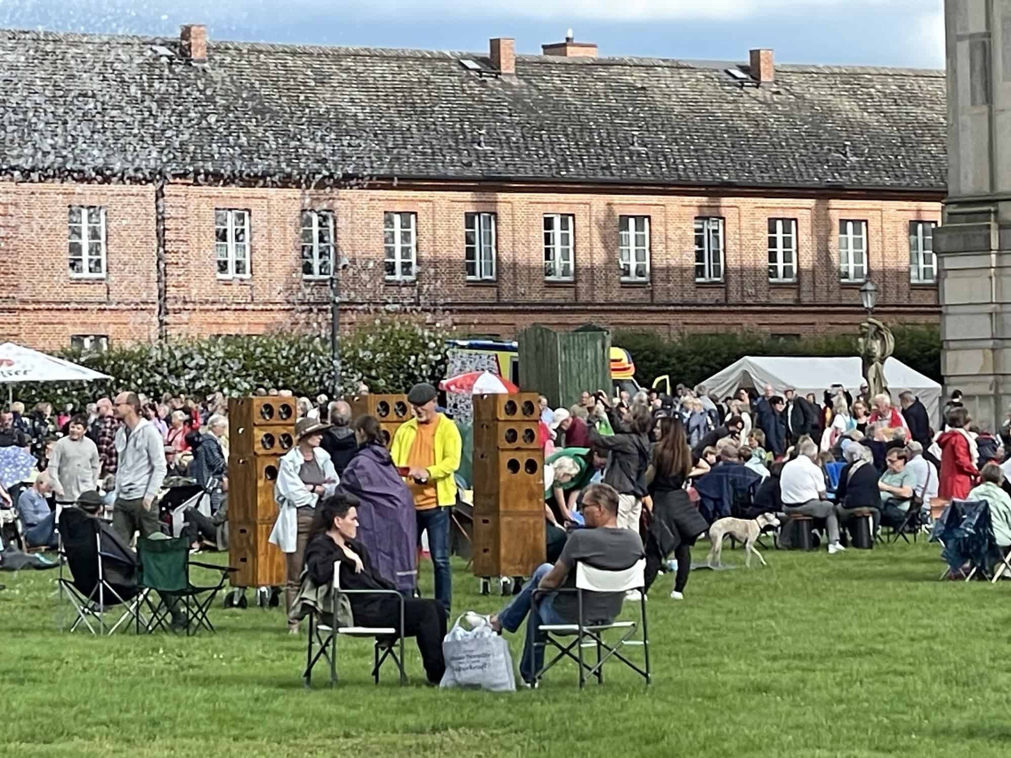 Picknickgäste mit rosafarbenen Nebengebäude im Hintergrund.