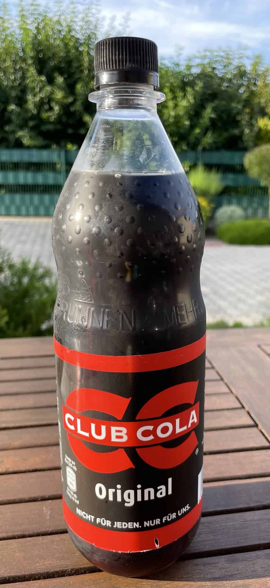 Gut gekühlte Petflasche Club Cola auf Holtgartentisch.