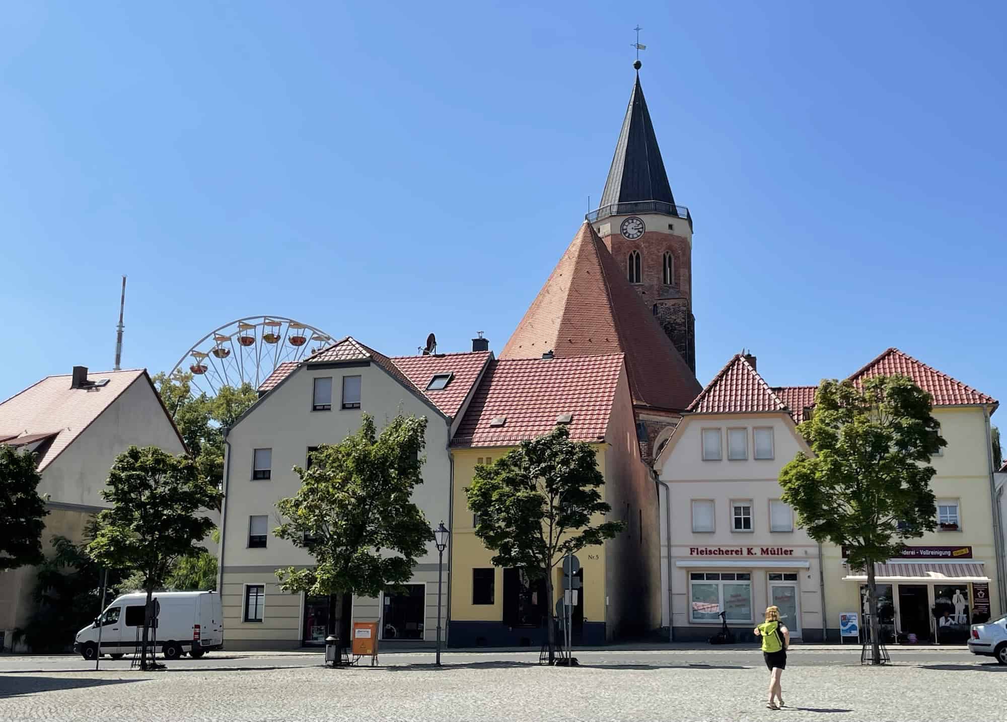Skyline von Calau mit der Kurche im Hintergrund, einem Riesenrad an der Seite und Häusern im Vordergrund sowie der Marktplatz.
