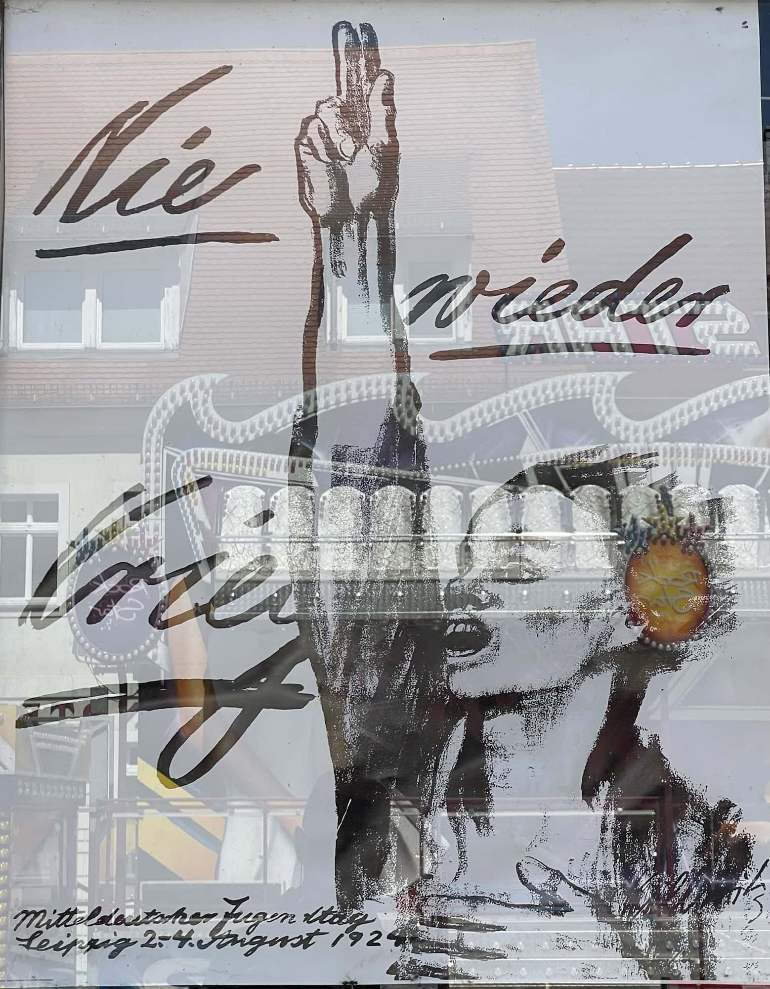 Das 'Nie wieder Krieg'-Schriftzug auf Käthe-Kollwitz-Plakat mit stulisierter jugendlicher Person mit erhobener Schwurhand.