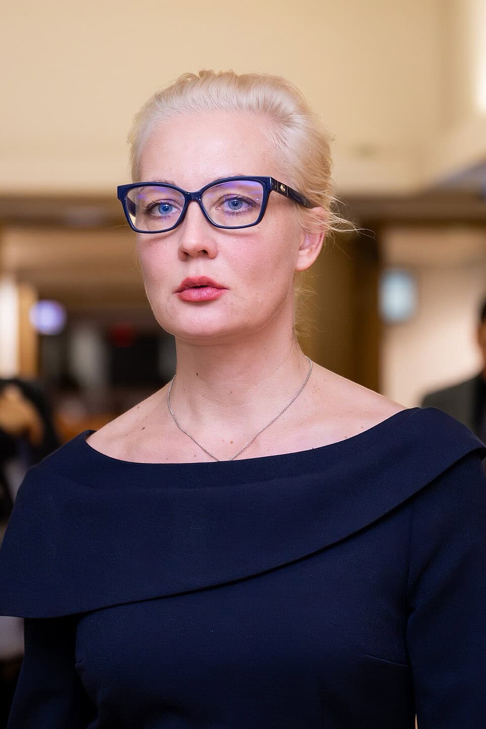 Portrait von Julija Nawalnaja, schwarze markante Brille und dunkelblaues Kleid.