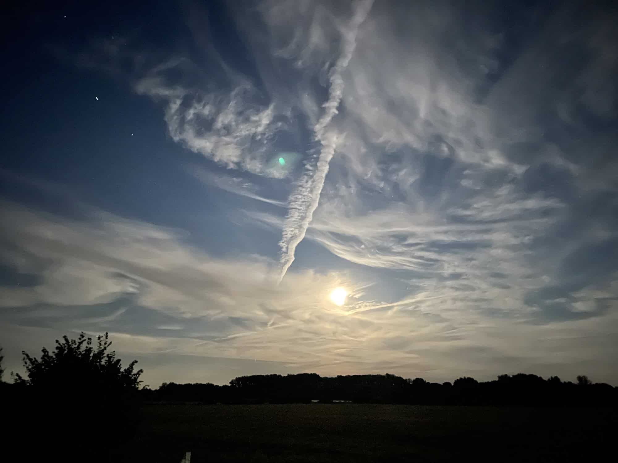 Der abendliche dunkle Himmel mit helken Mond zwischen Wolken.