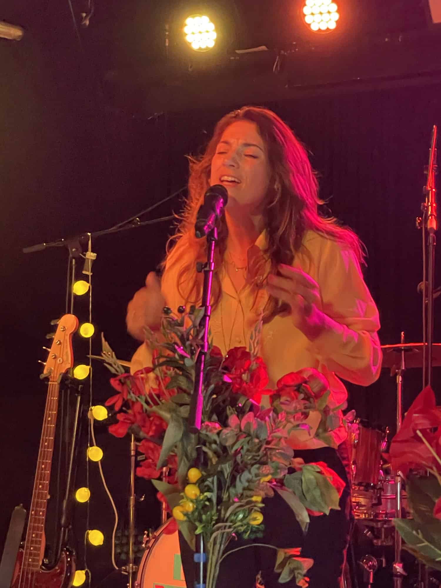 Luca Vasta singend und klatschend am Standmikro mit Blumenschmuck.