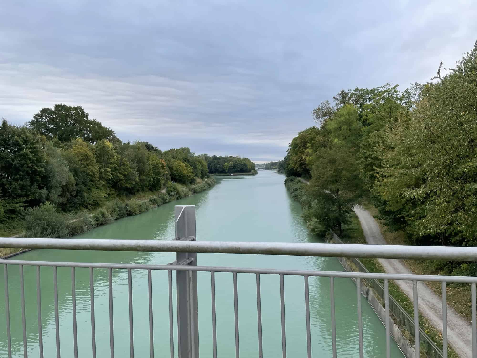 Mittellandkanal und links und rechts davon Bäume mit Metallgeländer der Brücke im Vordergrund.