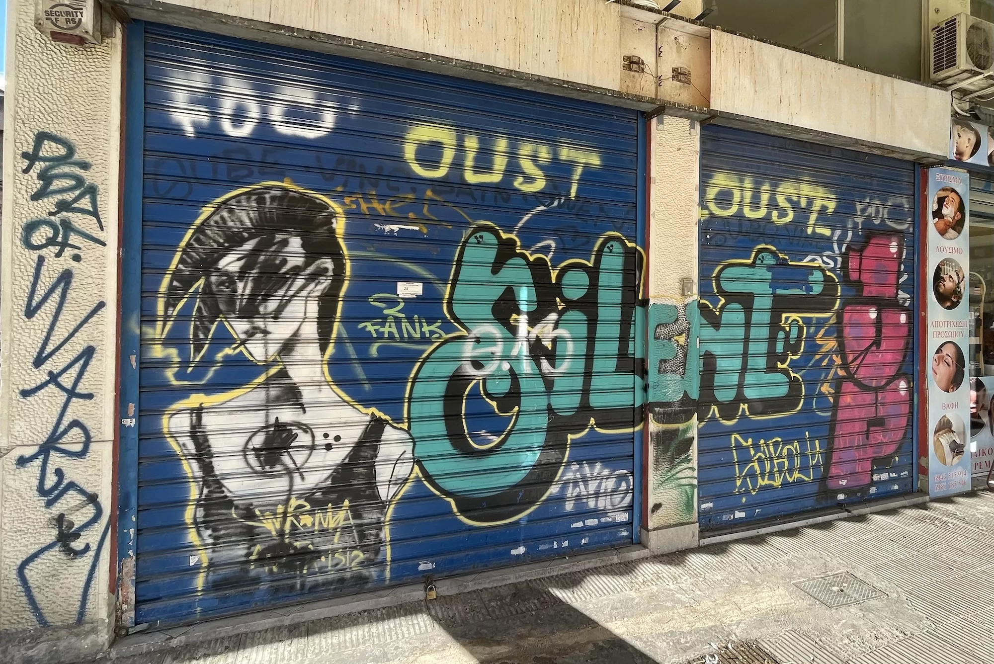 Graffitiws auf zwei Schaufensterrolläden eines Geschäftes.