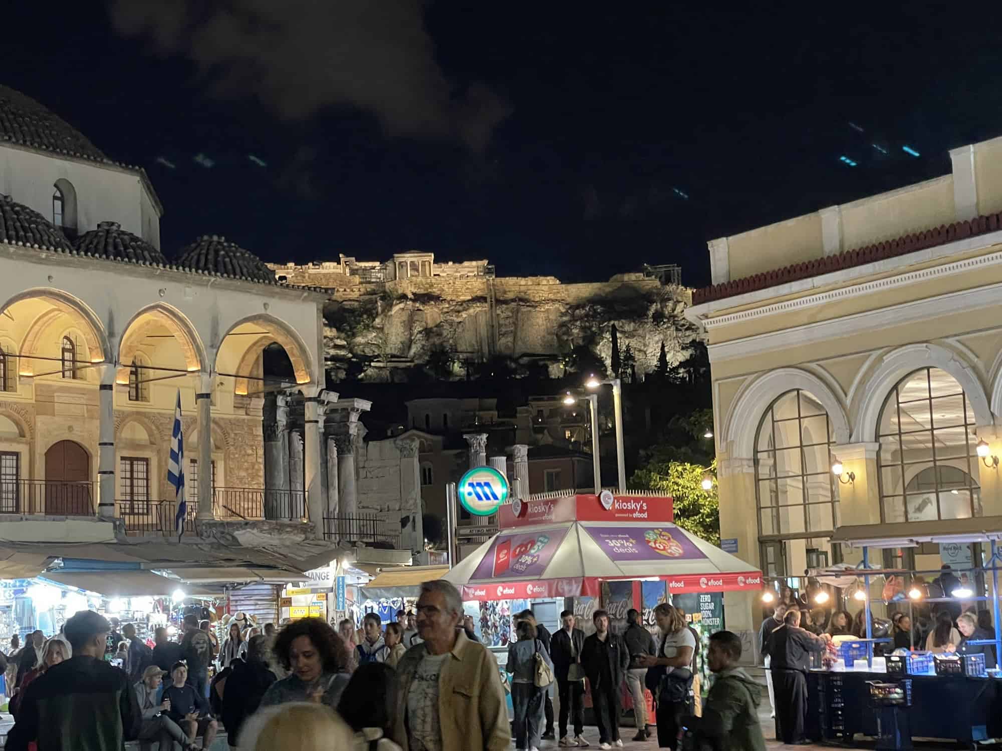 Das Das abendliche Getummel auf dem Platz in Monastiraki, im Hintergrund die beleuchtete Akripolis auf dem Berg.
