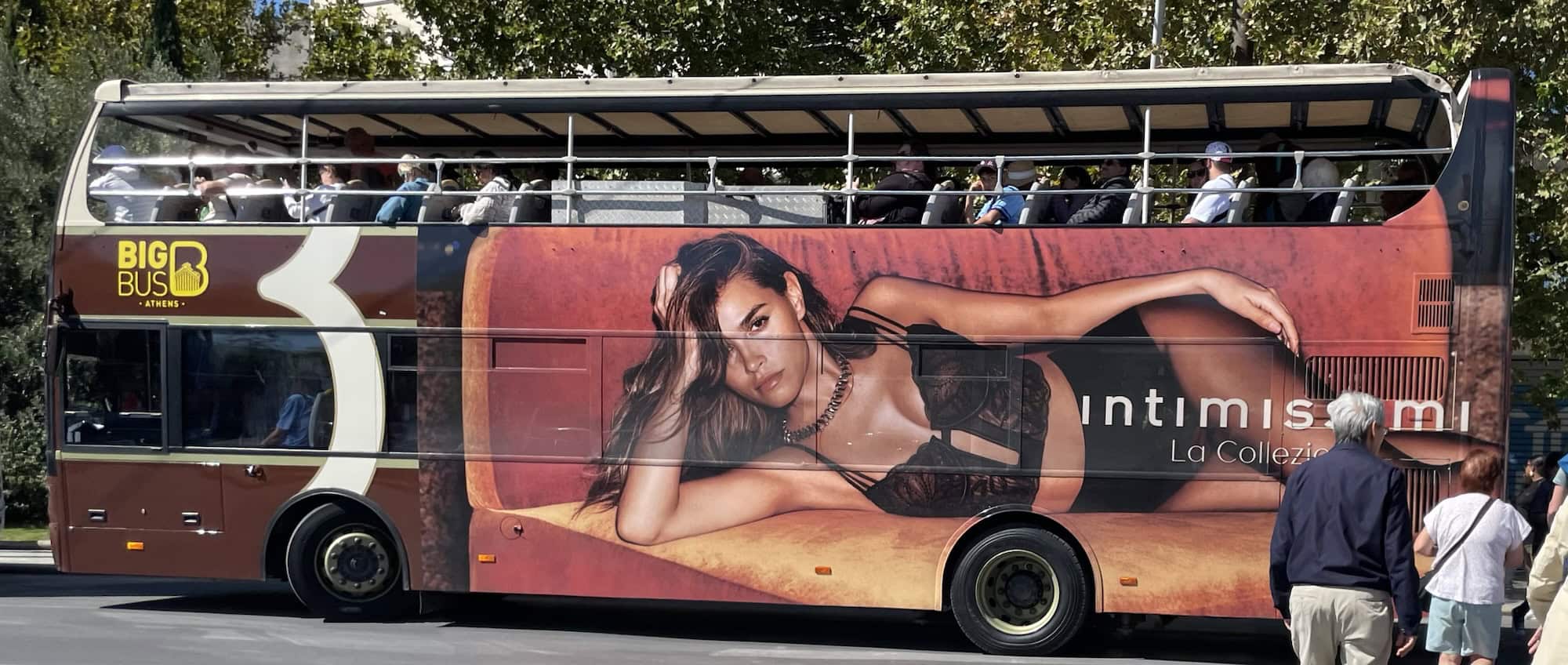 Ein roter Ausflugsbus mit überdimensionaler Reklsme eines liegenden Models in Dessous.