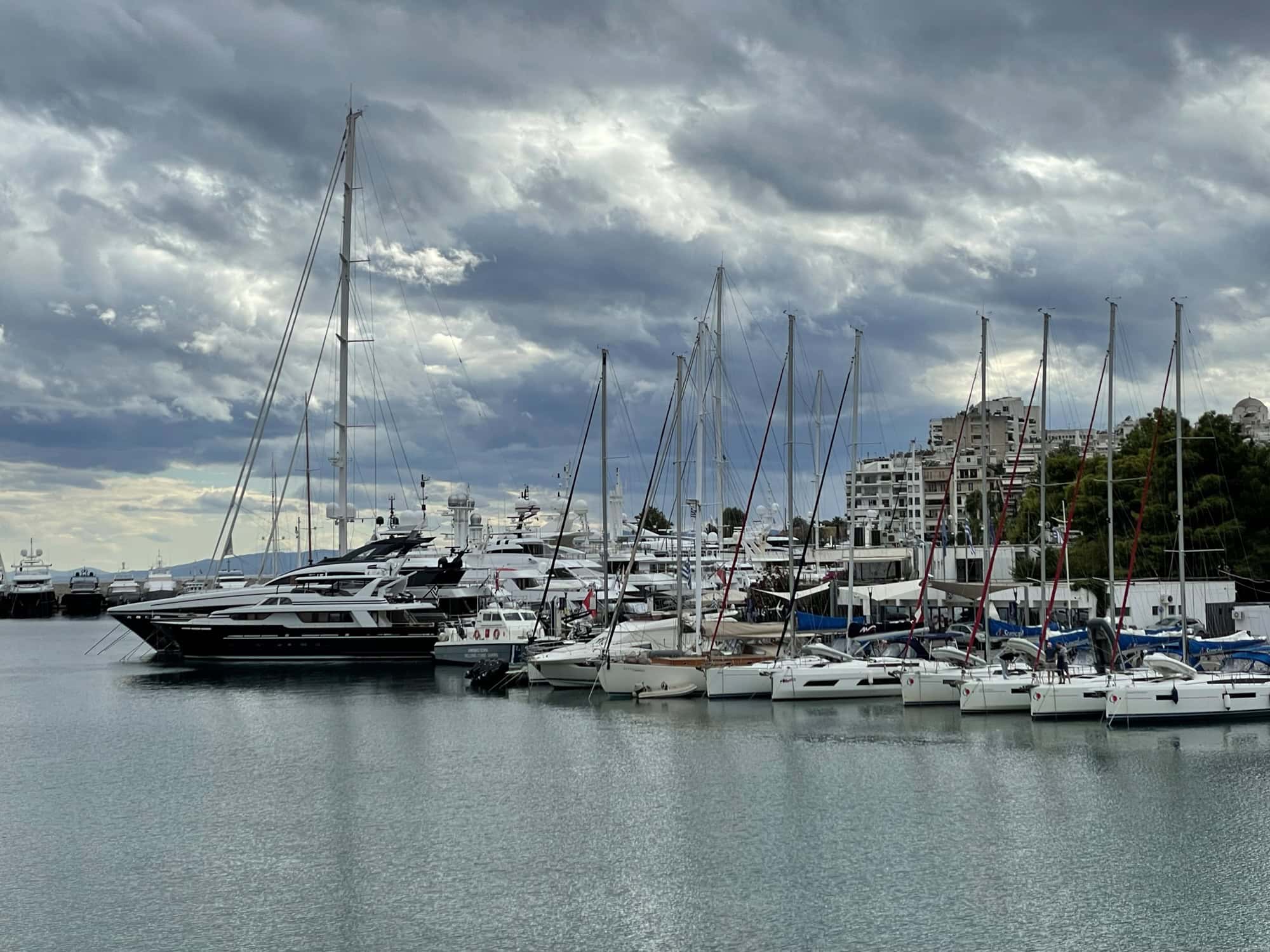 Viele geankerte Jachten im Hafen, dahinter Häuser.