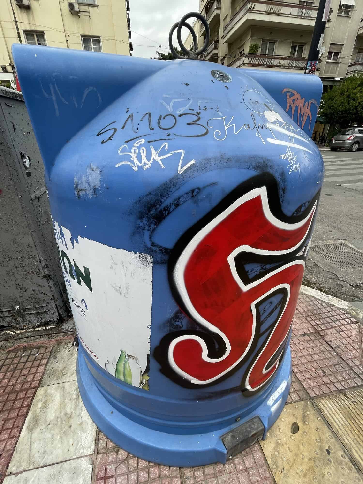 Blauer Altglascontainer mit großem roten 'H'.