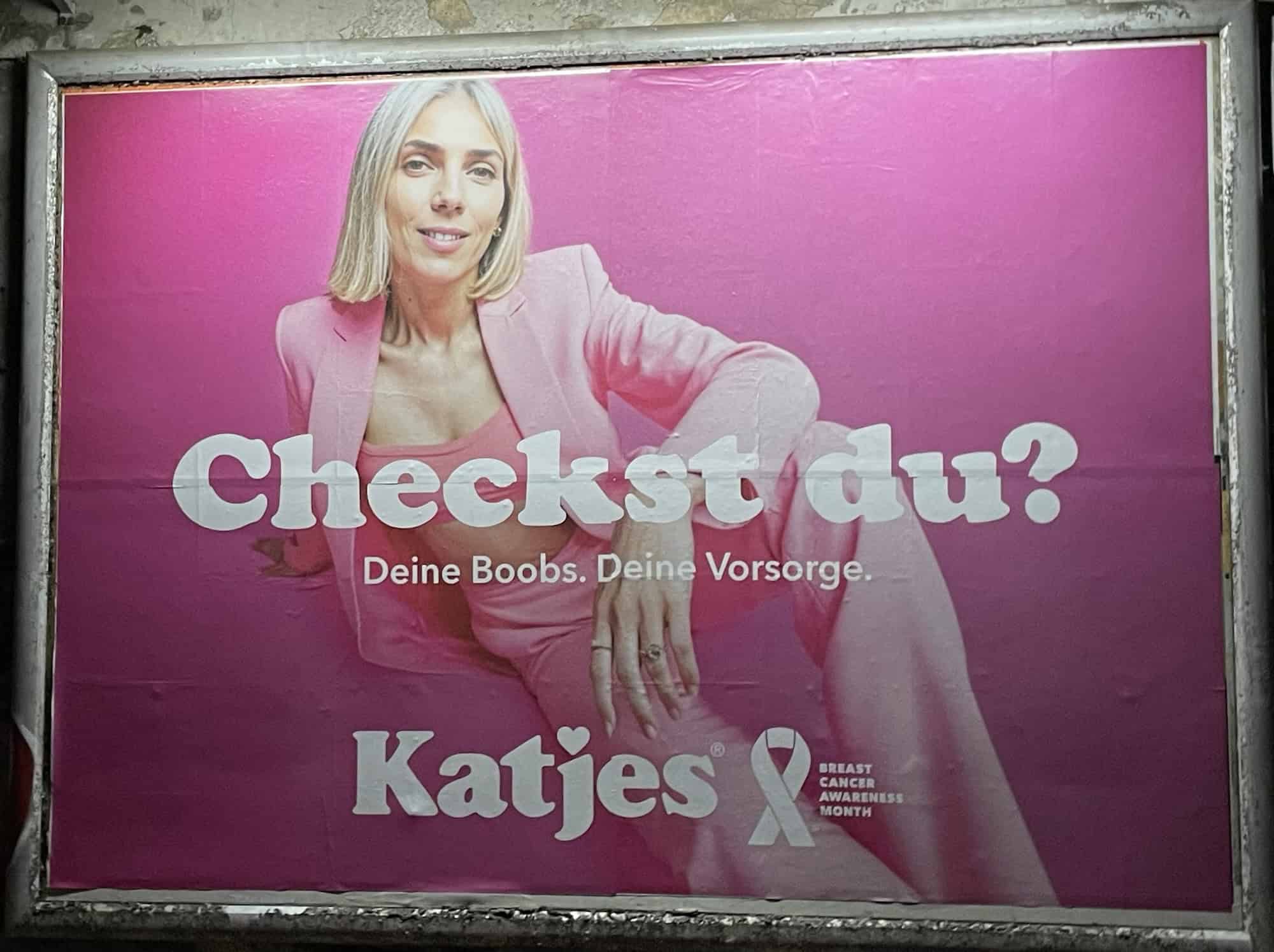 Außenwerbeplakat 'Checkst du!' rosa von Kajes mit abgebildetet Frau zum Brustkrebsmonat Oktober, gleiche Frauenabbildung wie auf erdten Bild: silberblinde Frau mit Hose imund Blazer in rosa.
