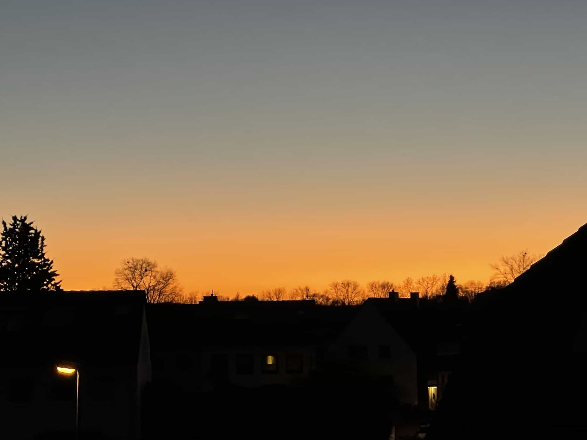 Abendlicher Blick über die Häuser mit orang-rotem Himmel.