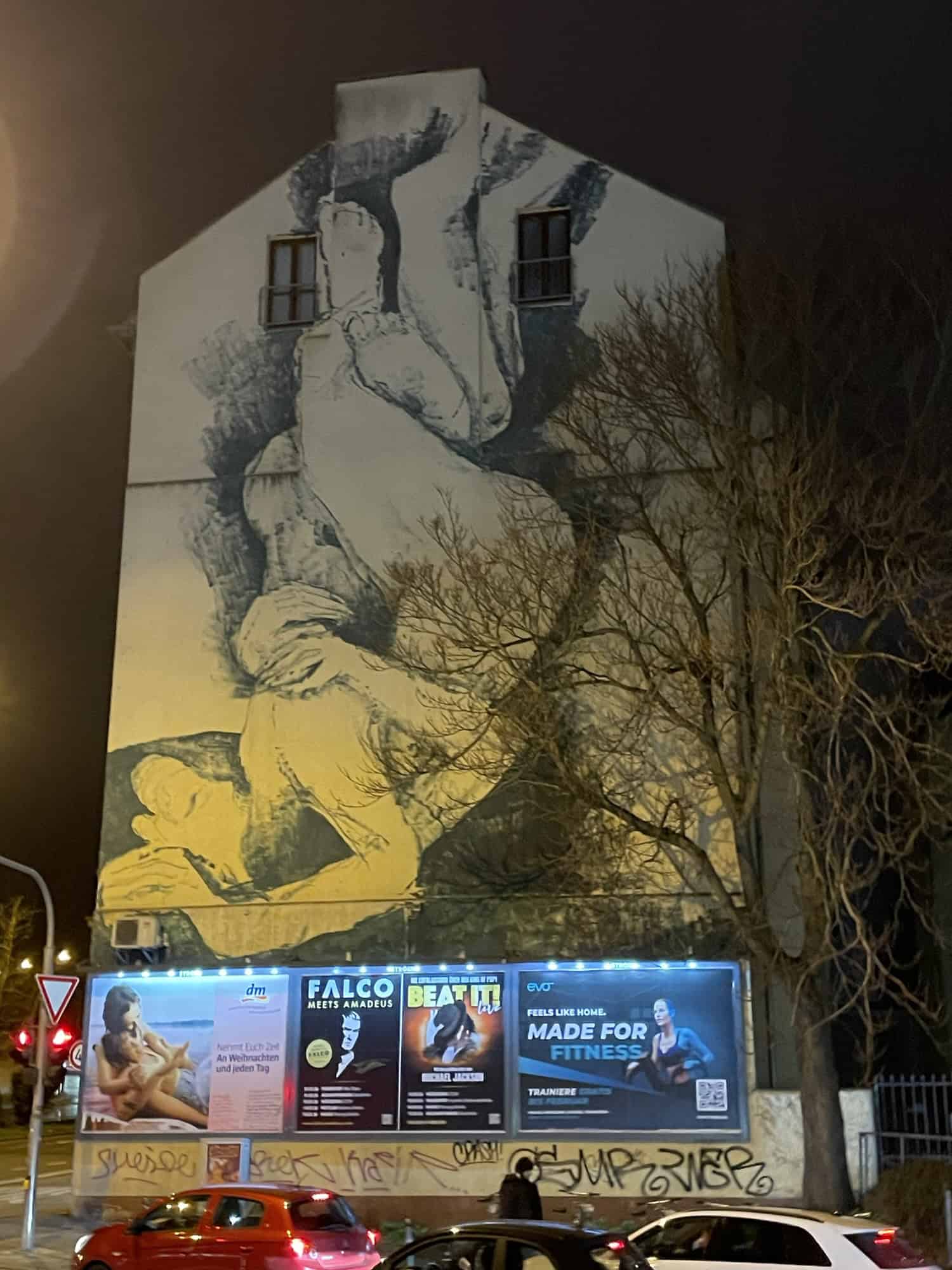 Seitenwand eines Mehrfamilienhauses mit Schwarz-Weiß-Bemalung von ineinander geschlungen Personen.