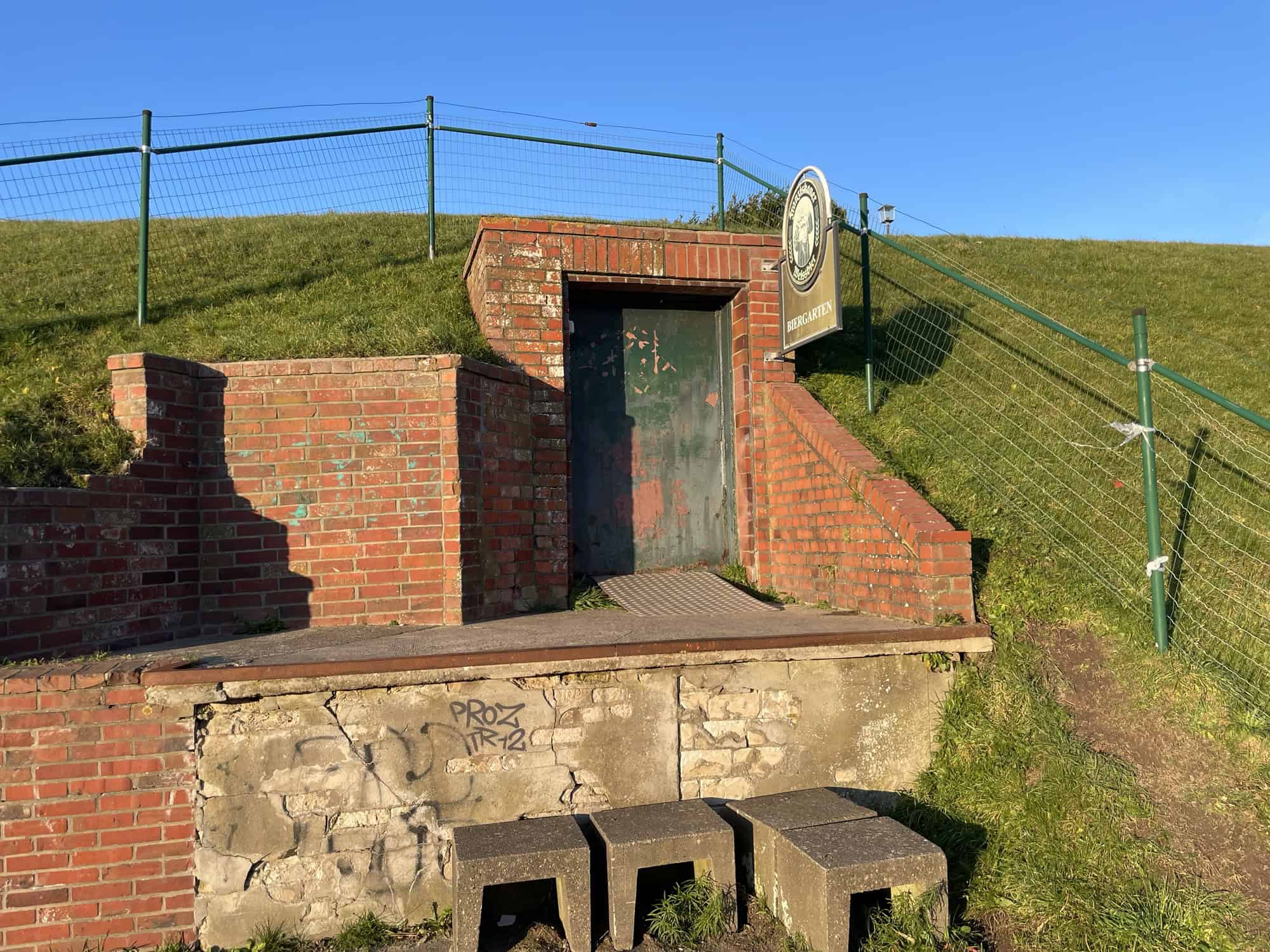 Der gesamze Biergartenbereich der nur aus Eingangstür in den Deich und Biergartenschild besteht.