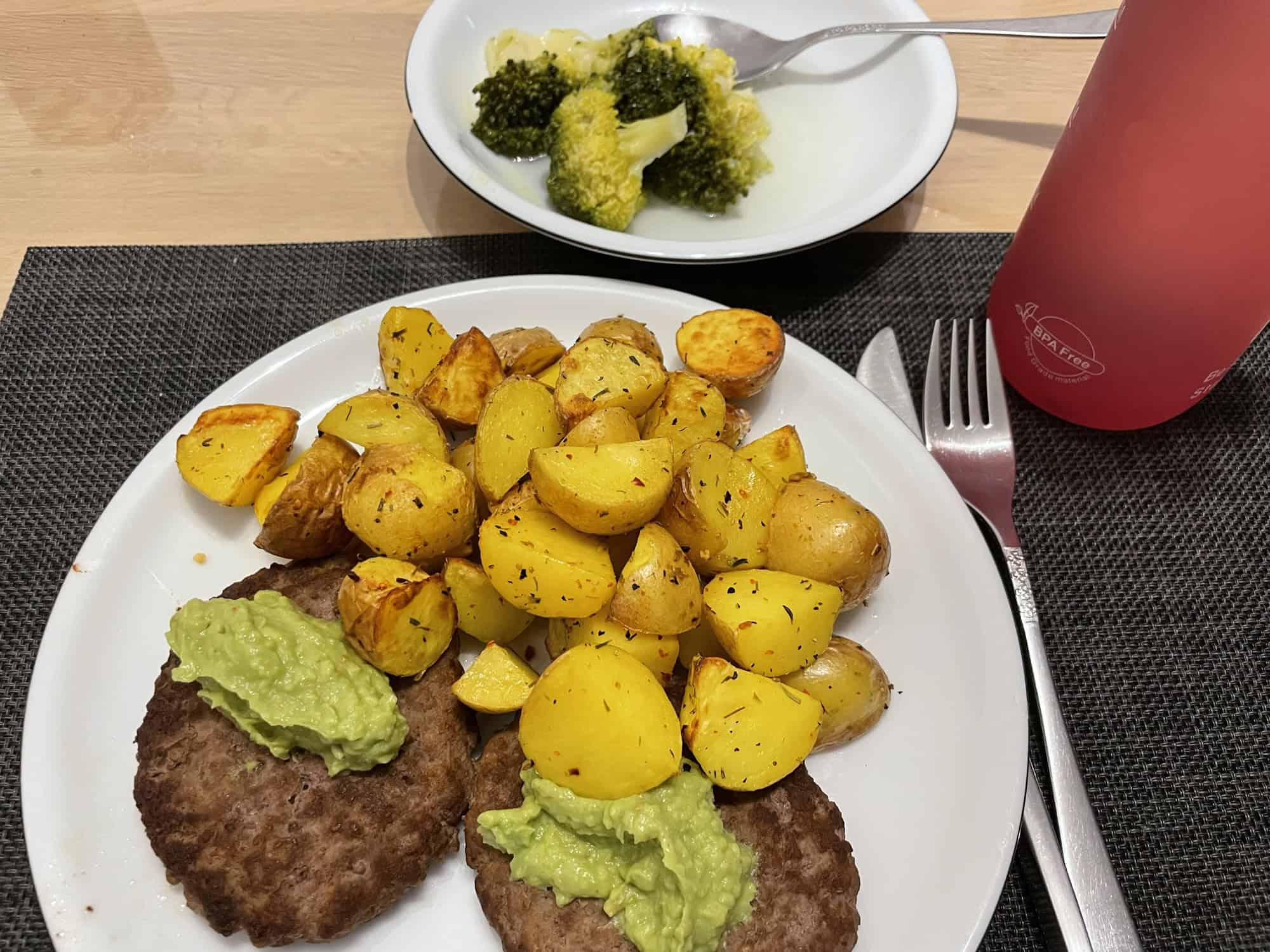 Vegane Hackpeddies darauf Avocadocreme, frittiertr Kartoffeln und Brokoli.