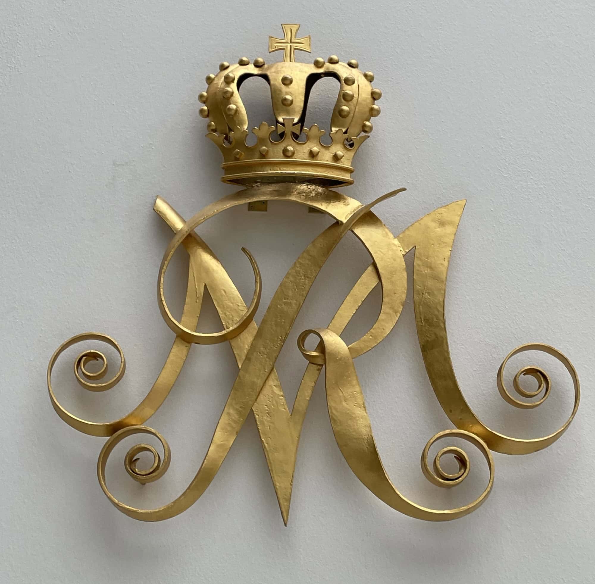 Wandschmuck goldene Krone mit goldenem 'MR' im Henriettenstift Hannover darunter.