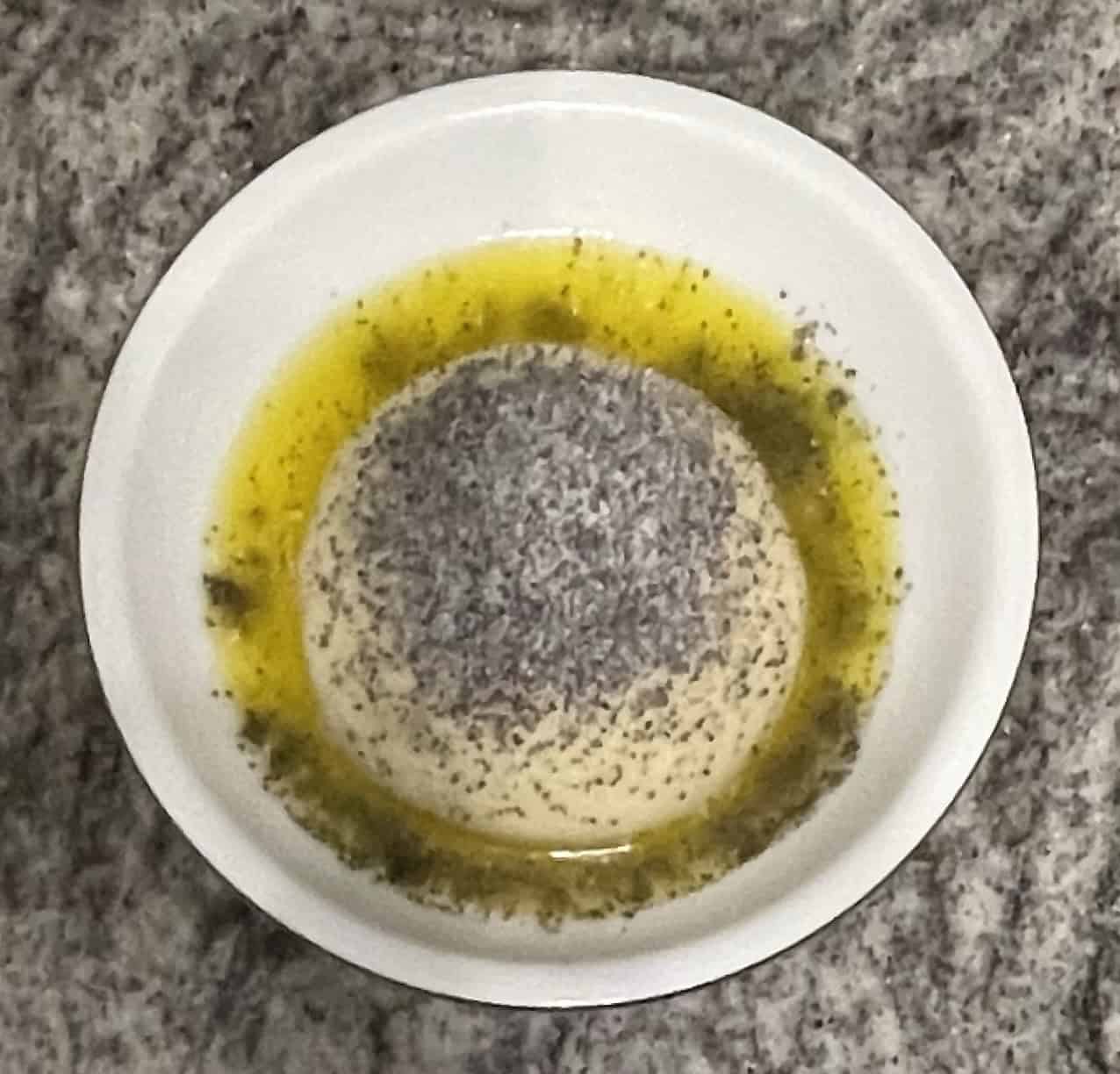 Teller mit Germknödel, zerlassener Butter und Mohn-Puderzucker auf Granitarbeitsplatte.