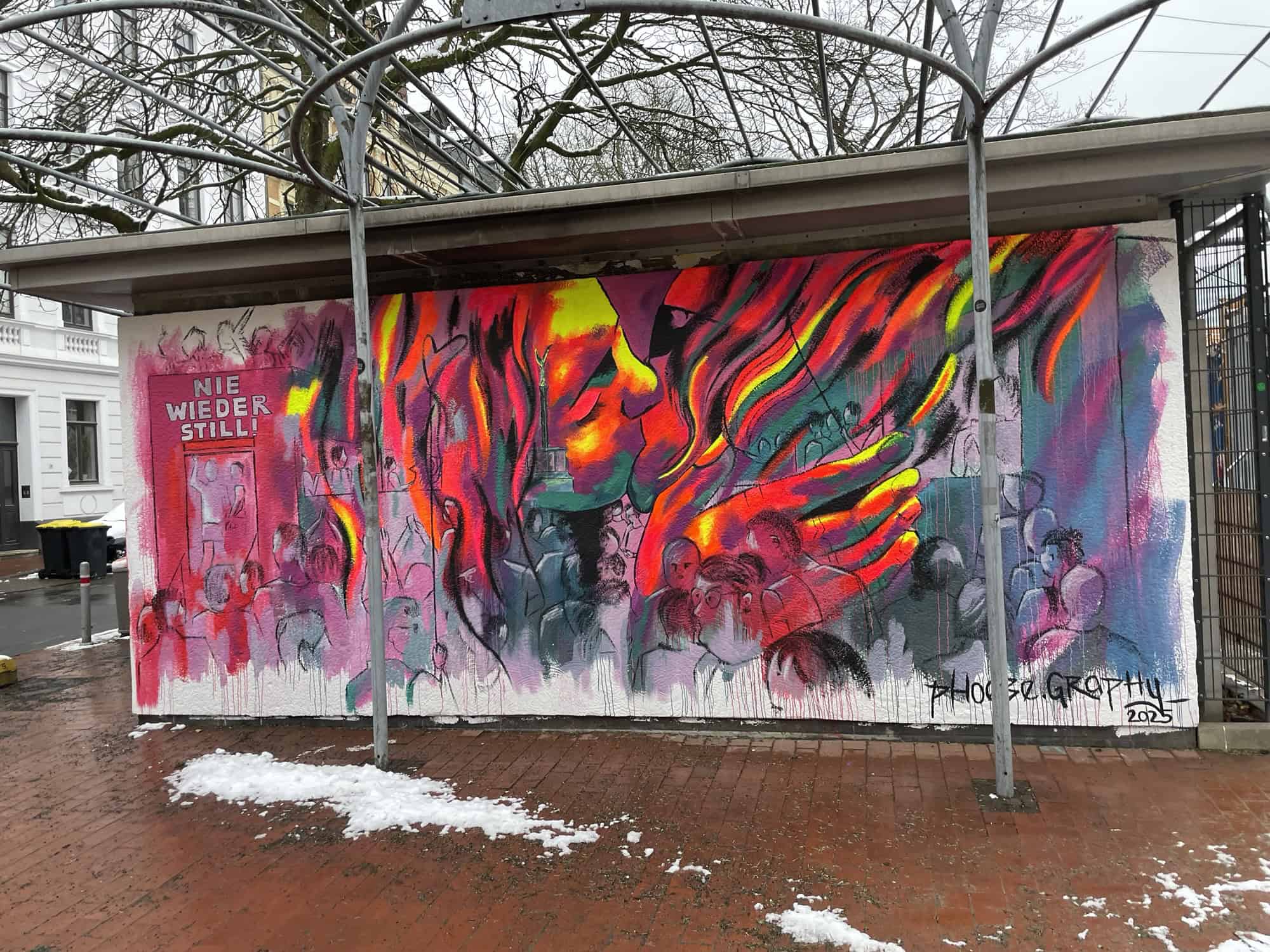 Großbild auf Häuschen mit 'Nie wieder still!', Flammen und zwei sich küssenden Gesichtern.