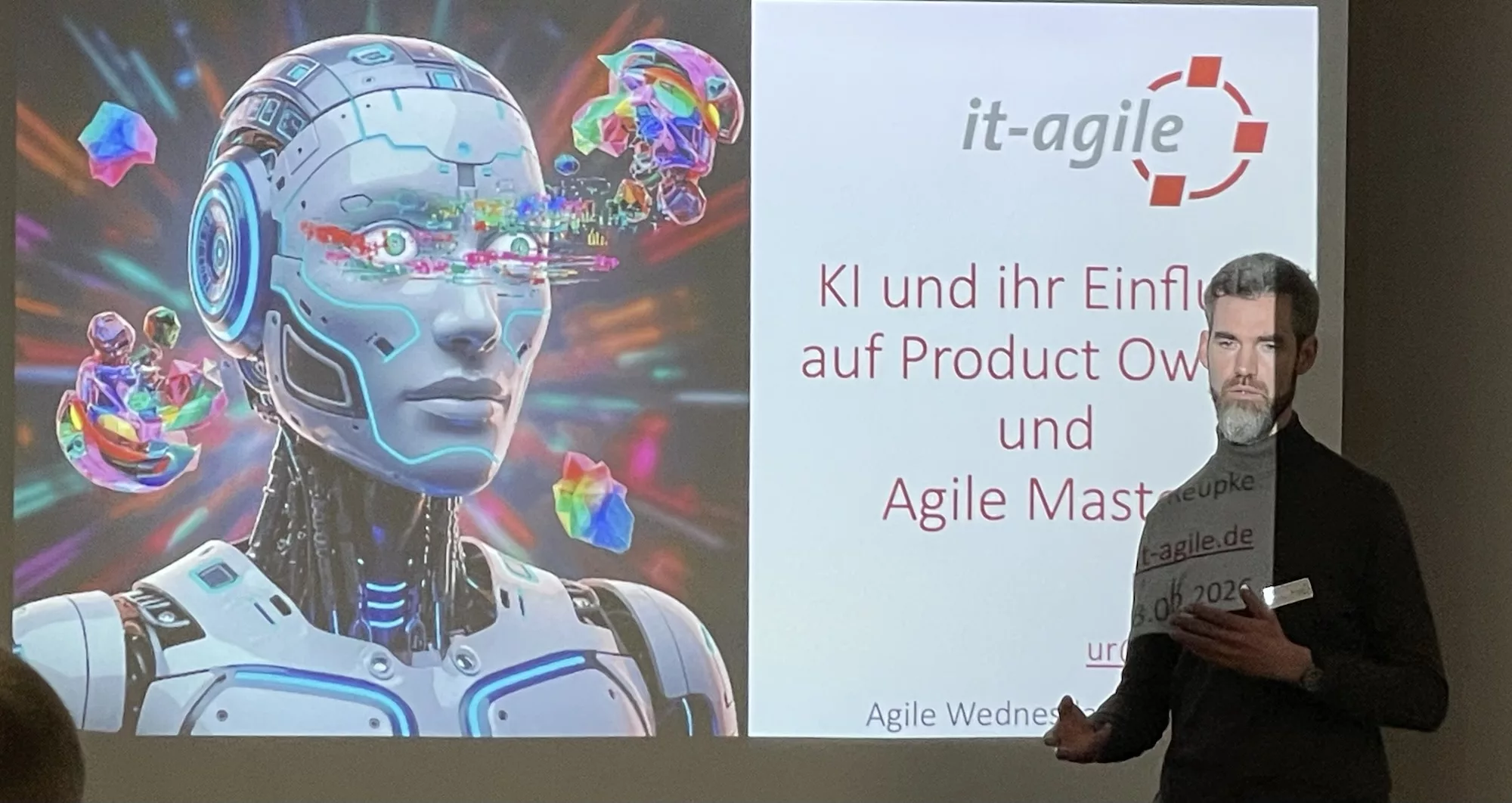 Urs vor Startfolie des Vortrags, durch Beamer an die Wand hinter sich geworfen.