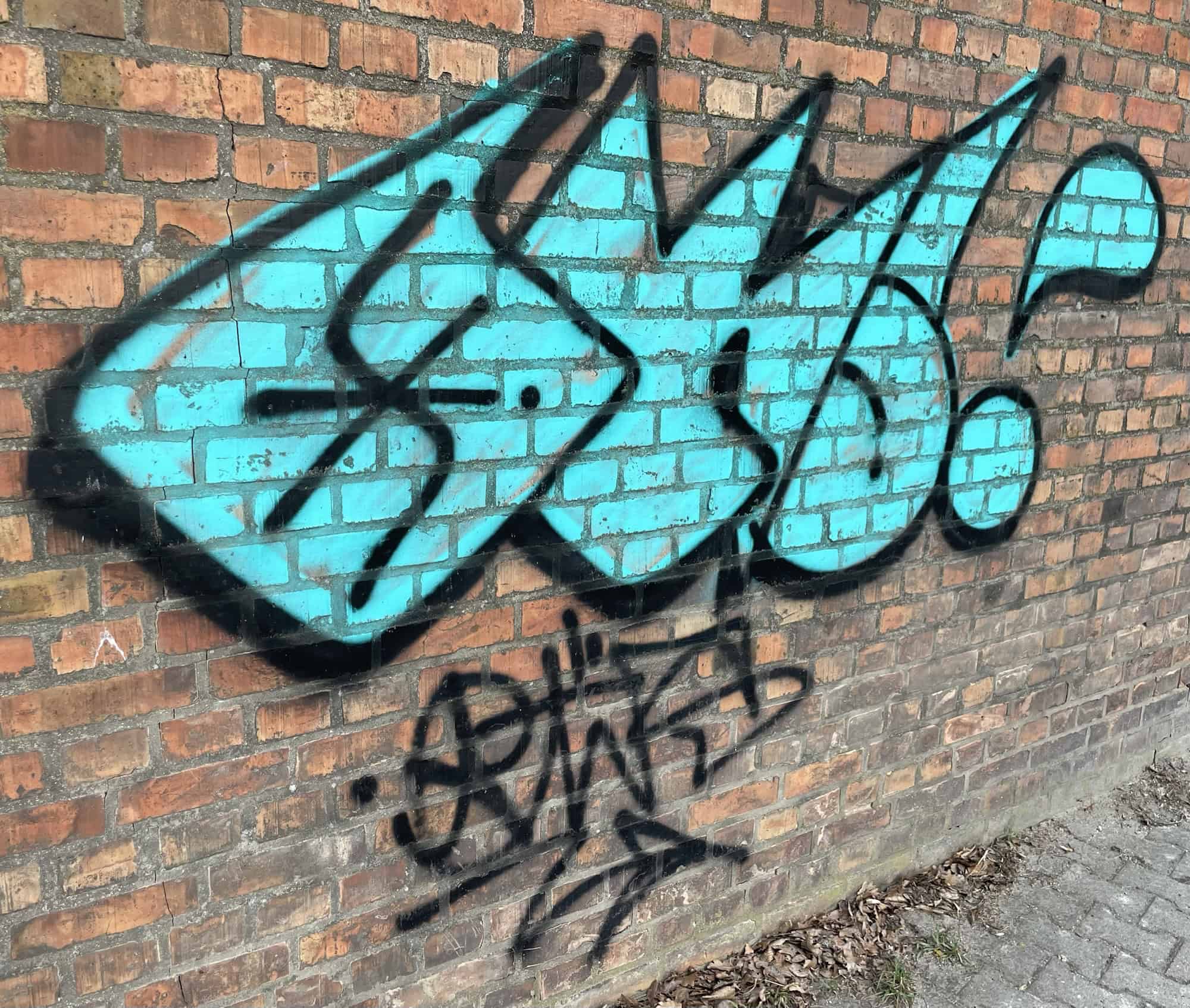 Hellblaues Worttagging in Hellblau an roter Backsteinwand.