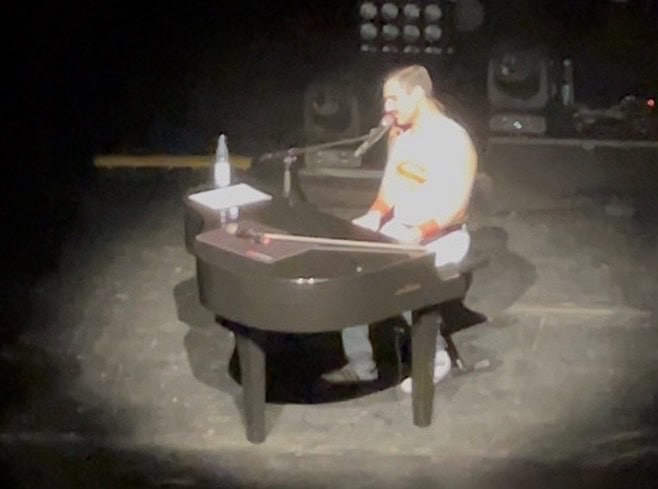 Der Freddie Mercury Sänge sitzend am schwarzen am E-Piano.