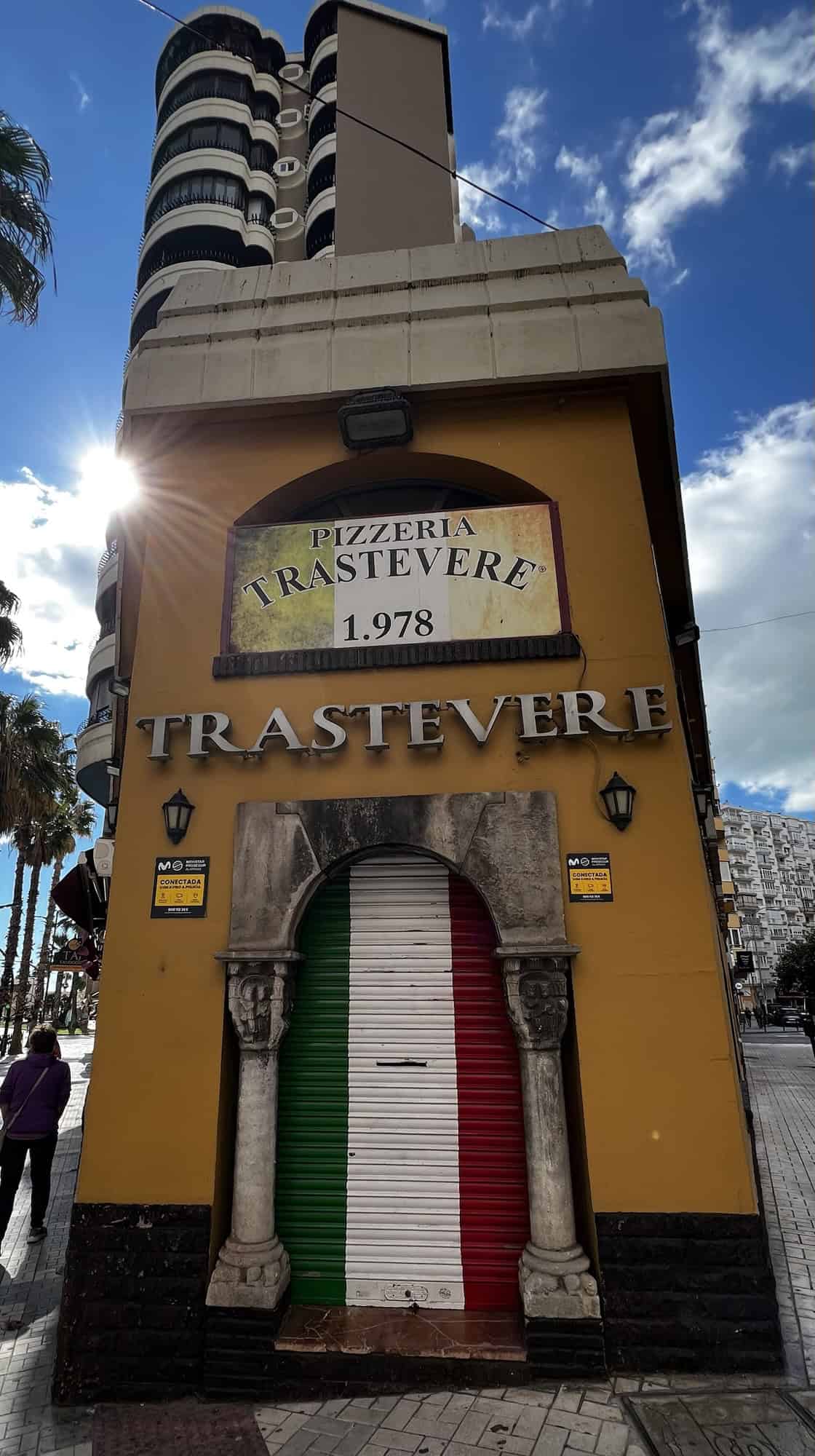 Gelbes schlankes Haus, in der die Pizzeria Trastevere in Malaga ist.