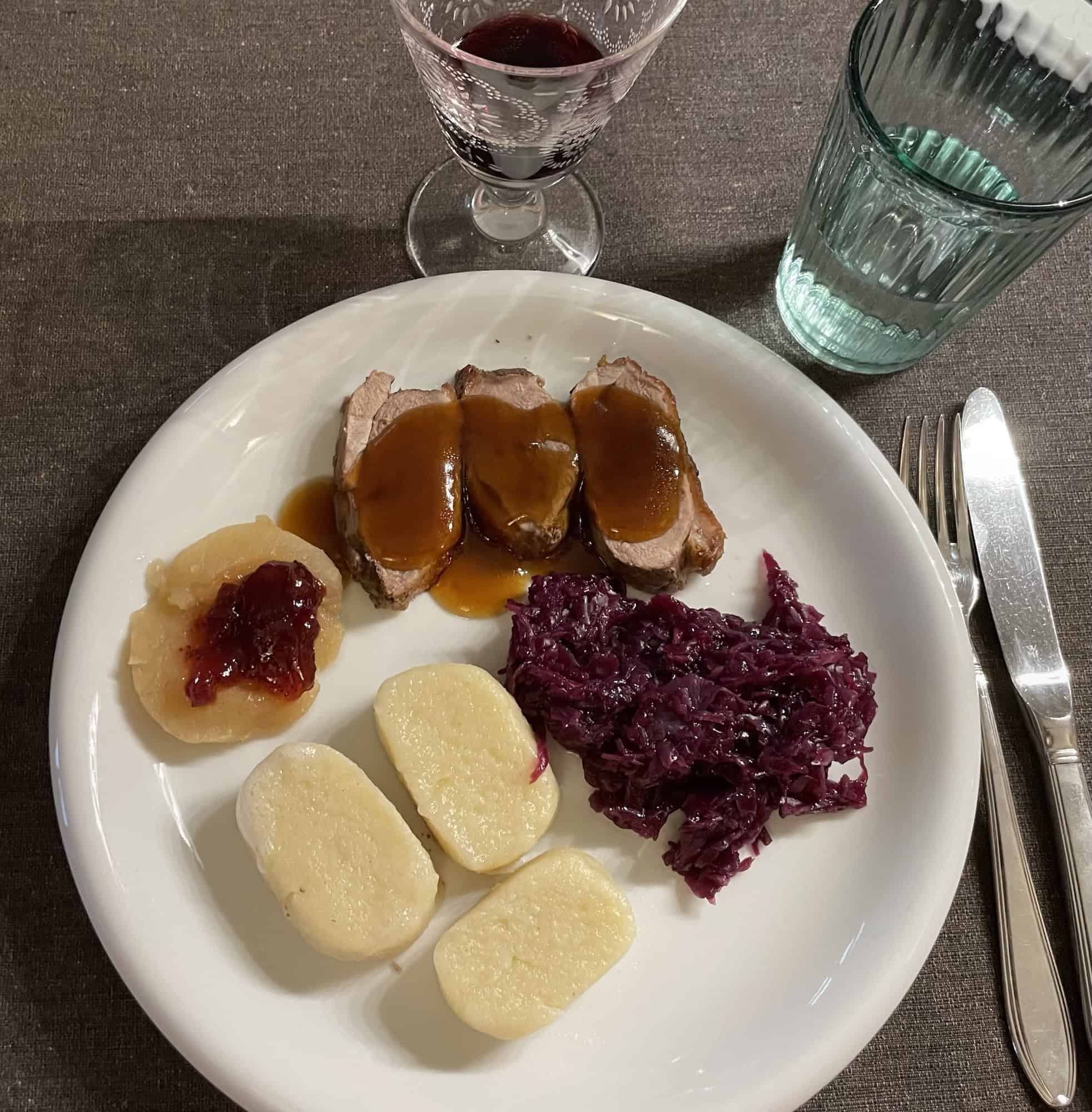 Scheiben von Ente an Rotkohl und weißen Knödeln.