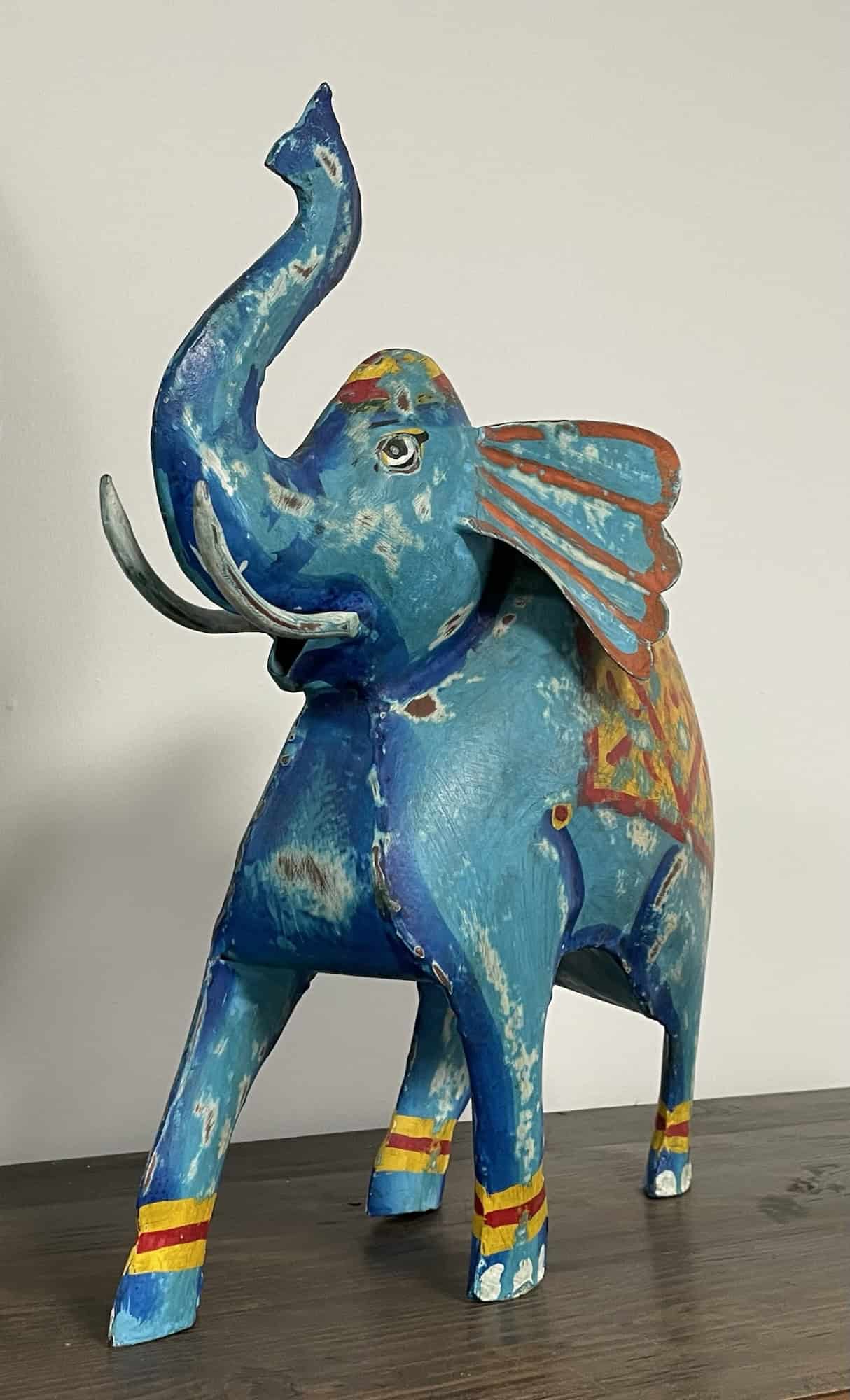 Blau-bunte Holzfigur mit erhobenem Rüssel.