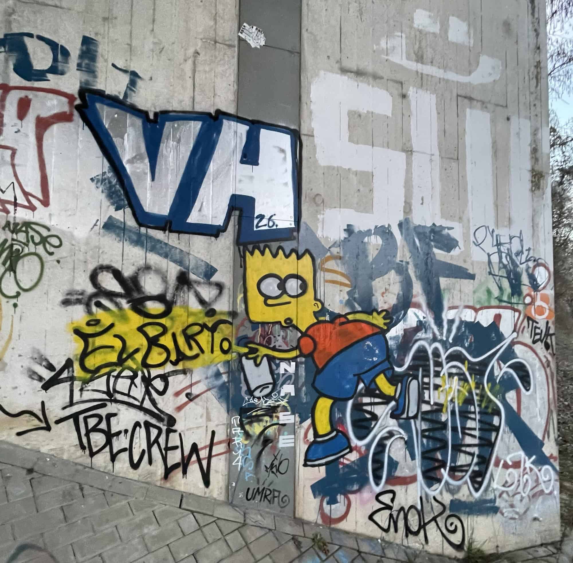 Brückenbetonwand mit Graffities und Bart Simpson in ddr Mitte.