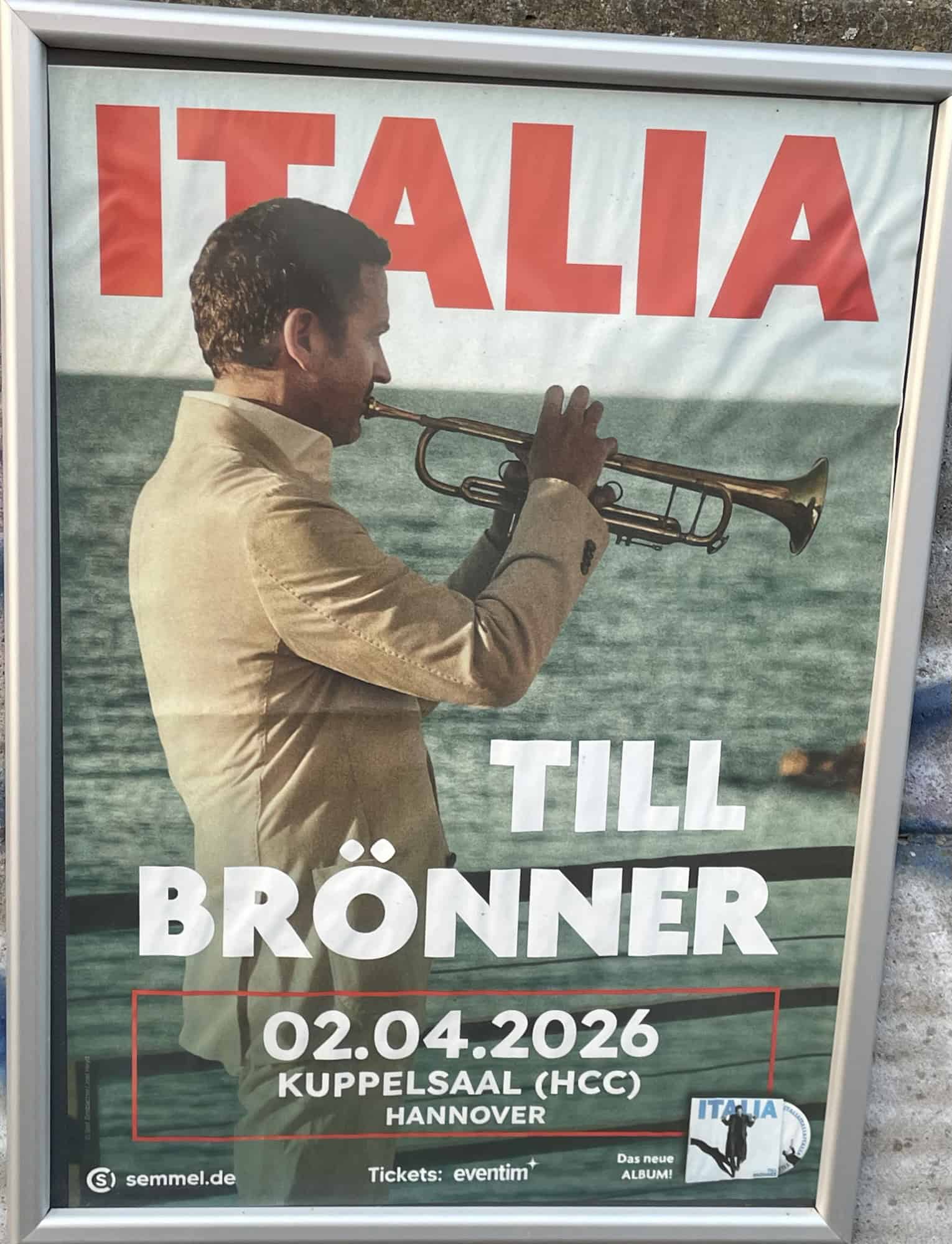 Konzertplakat von Till Brönner zur Italia-Tour. er trompetend in sandfarbenen Sakko an Promenade mit Meer im Hinzergrund.