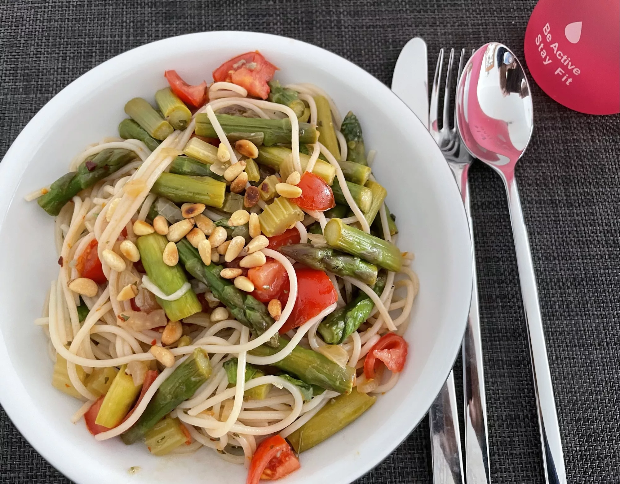 Gedeck mit Teller Spaghtti an grünem Spargel.