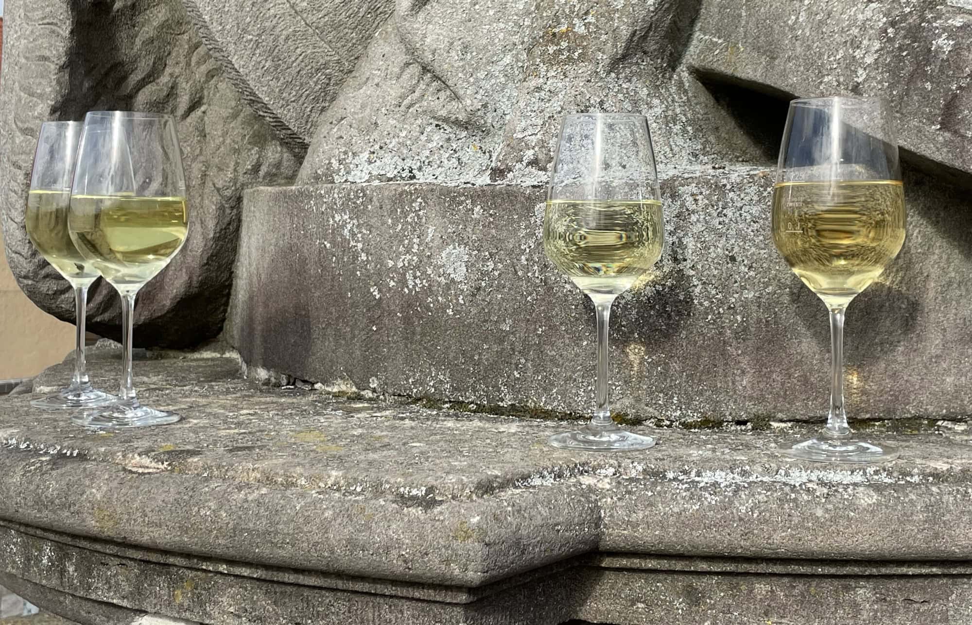 Weißweingläser auf dem Absatz einer Steinskulptur.
