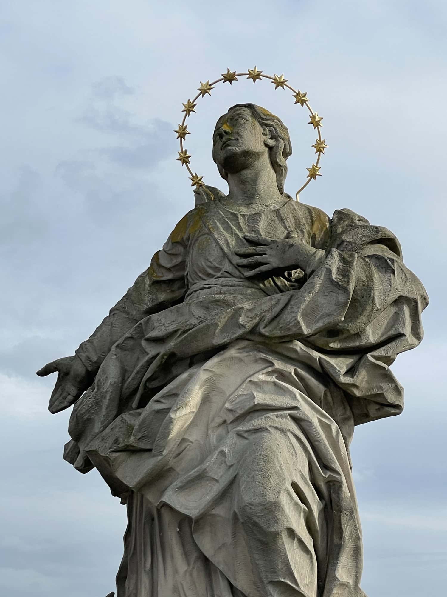 Heiligenskulptur aus Stein mit goldenem Heiligensschein.