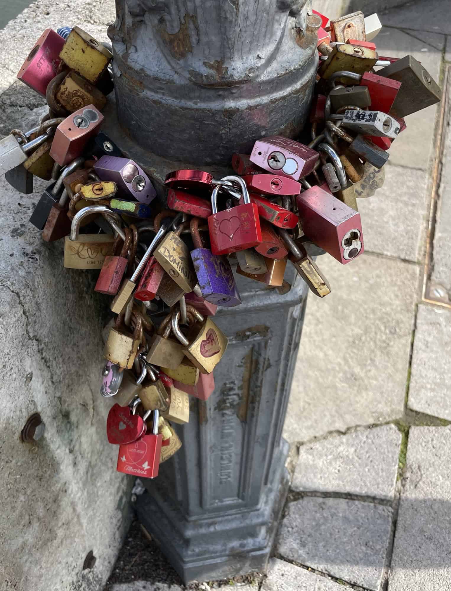 Großes Bündel Schlösser um eine alte Metalllampenstange.