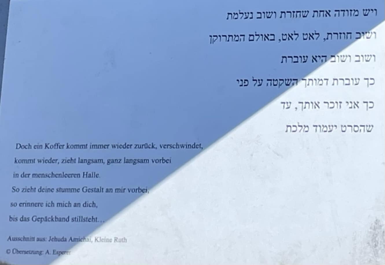 Inschrift auf deusch und hebräoisch: 'kommt wieder, zieht langsam, ganz langsam vorbei in der menschenleeren Halle. So zieht deine stumme Gestalt an mir vorbei, so erinnere ich mich an dich, bis das Gepäckband stillsteht...' Ausschnitt aus: Jehuda Amichai, Kleine Ruth © Obersetzung: A. Experer